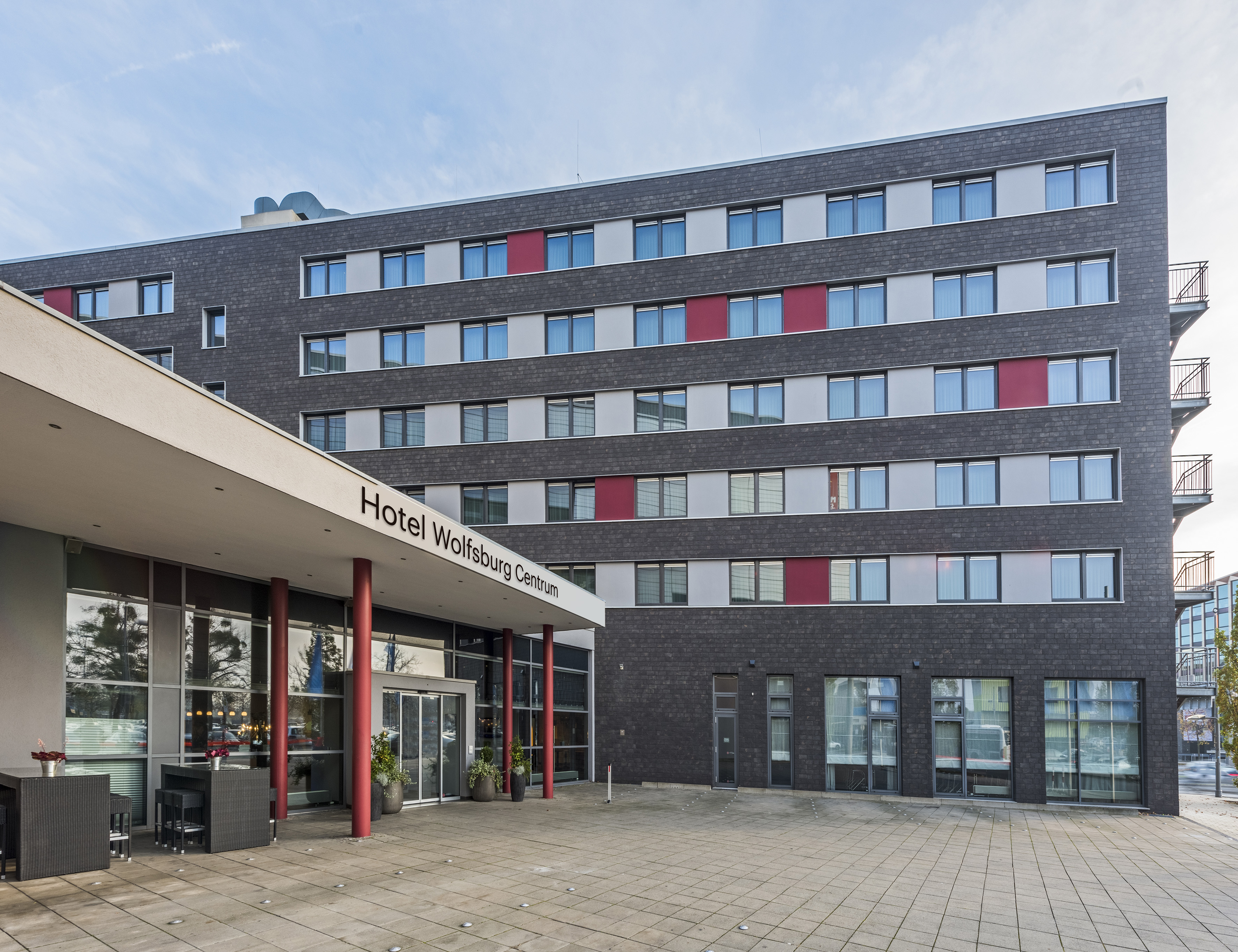 Hotel Wolfsburg Centrum: Modern exterior, dark facade, red accents, entrance.
