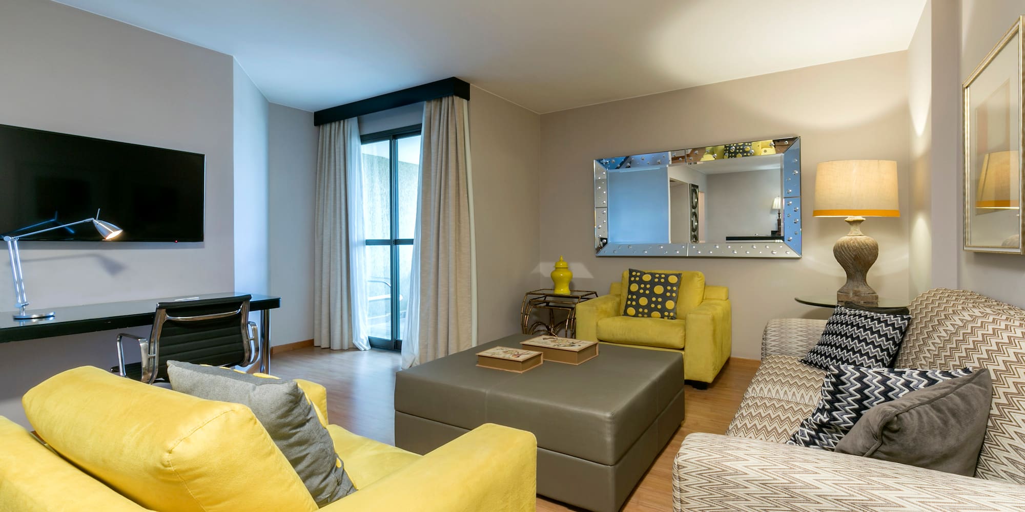 a living room with yellow couches and a mirror