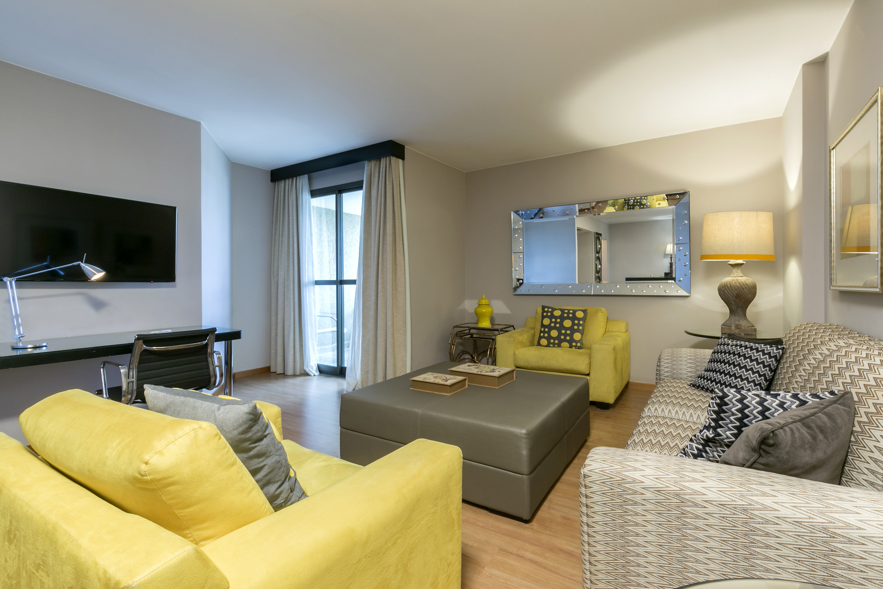 a living room with yellow couches and a mirror