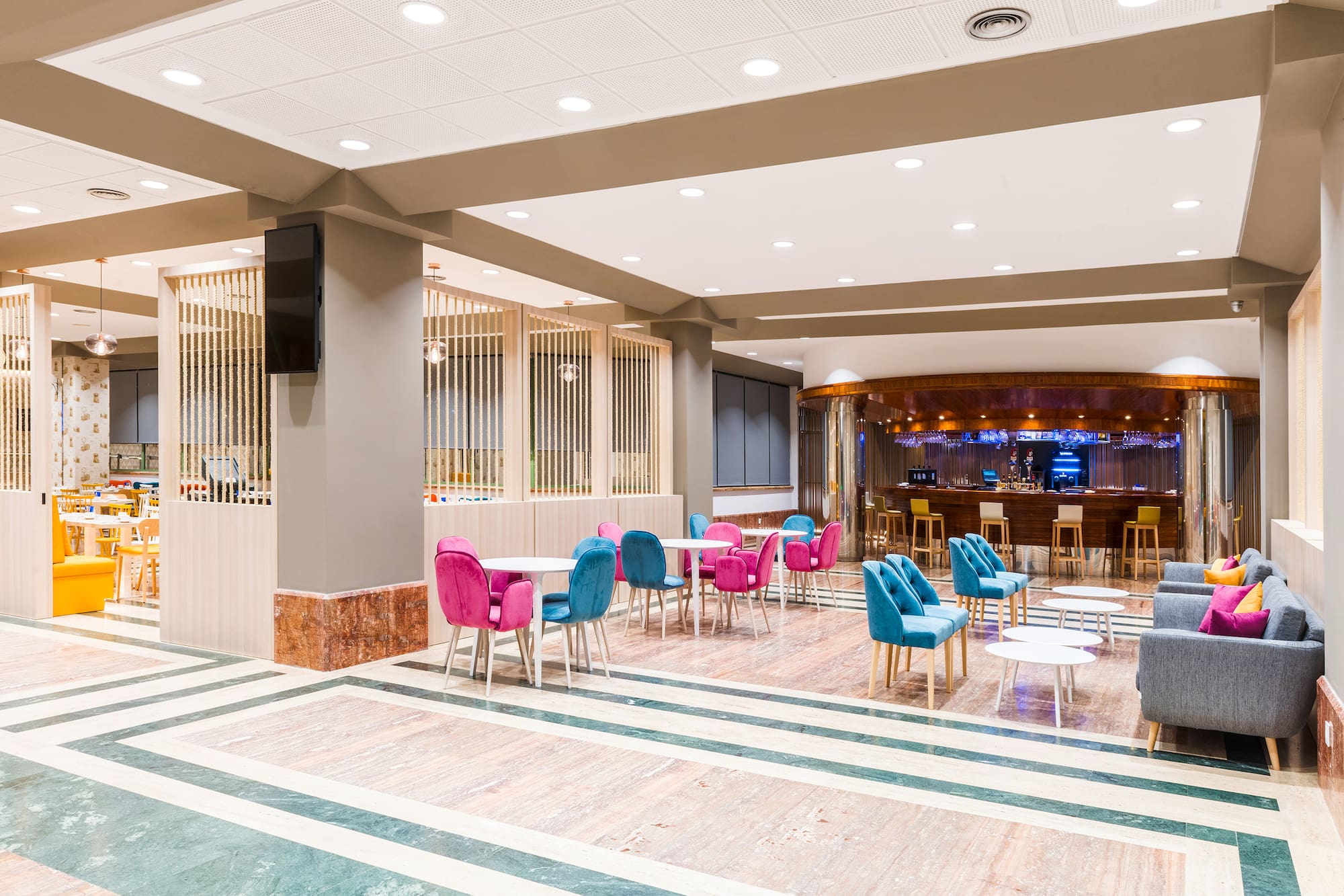 Hotel lobby bar and lounge with colorful seating and modern marble floor.