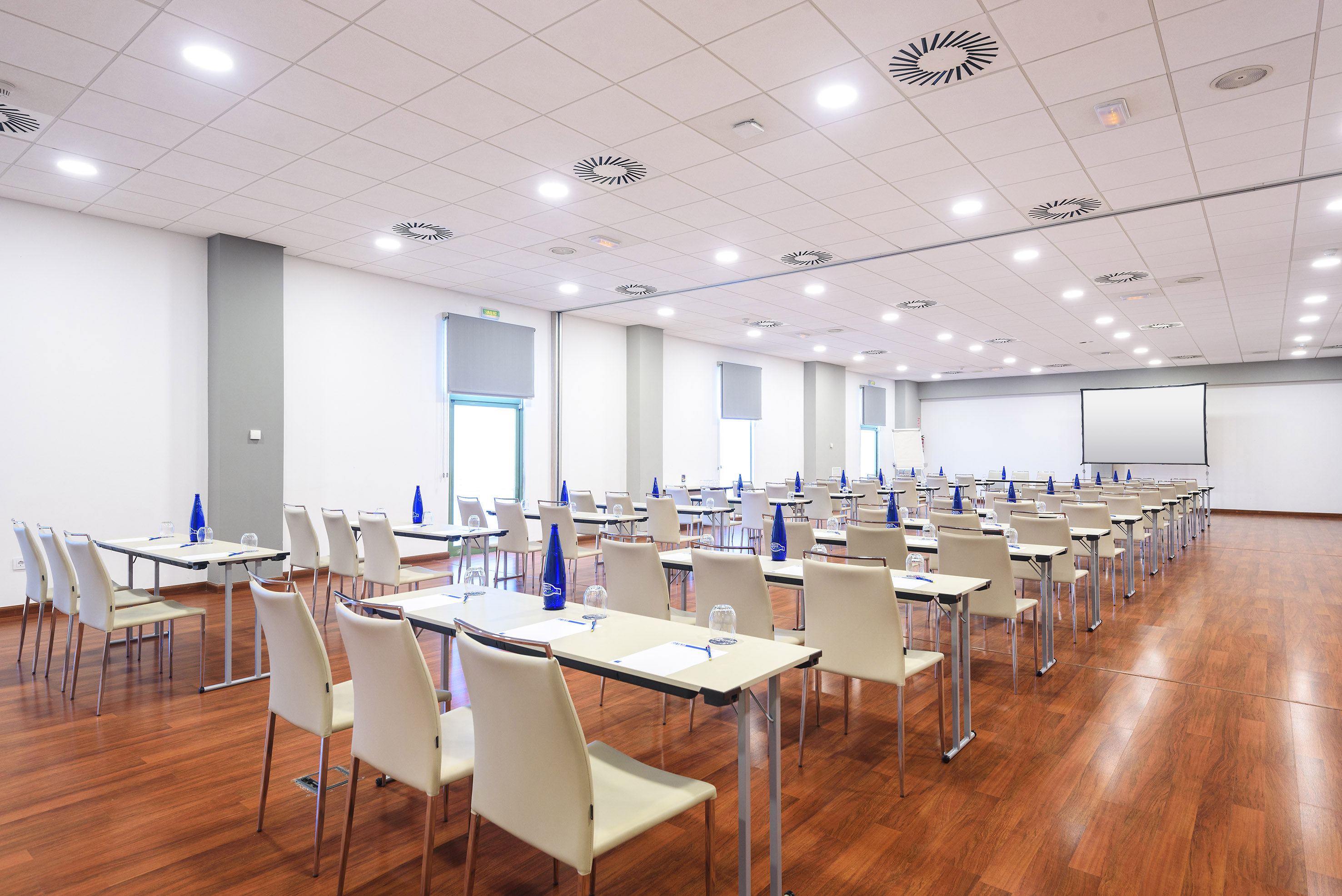 Modern conference room set up with tables, chairs, and projection screen.