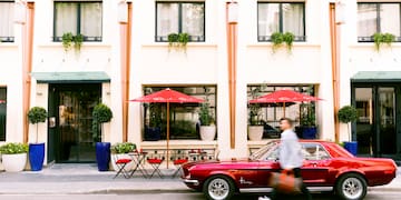 a man walking on the street with a red car
