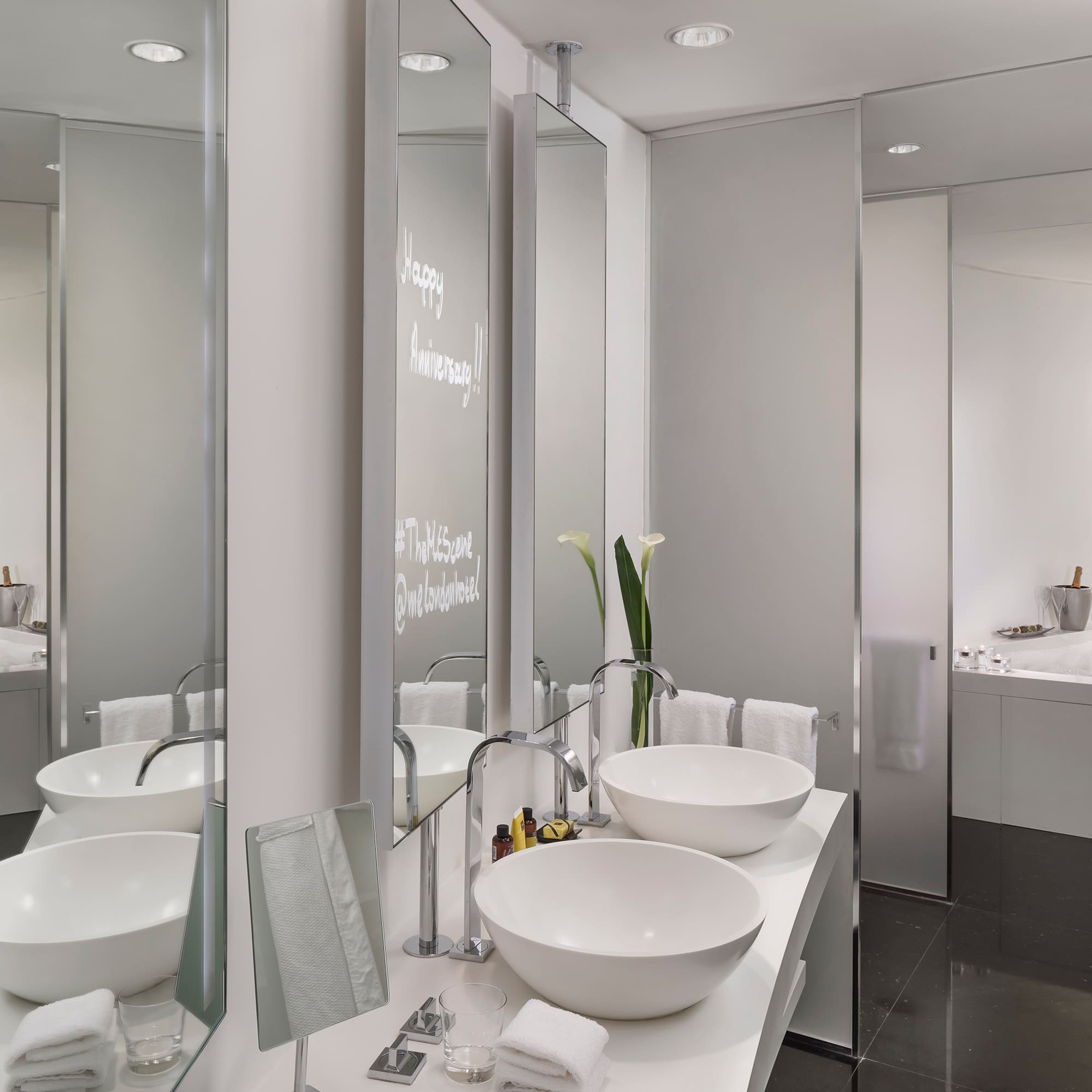Sleek modern hotel bathroom with double vanity, bowl sinks, and bubbly bathtub.