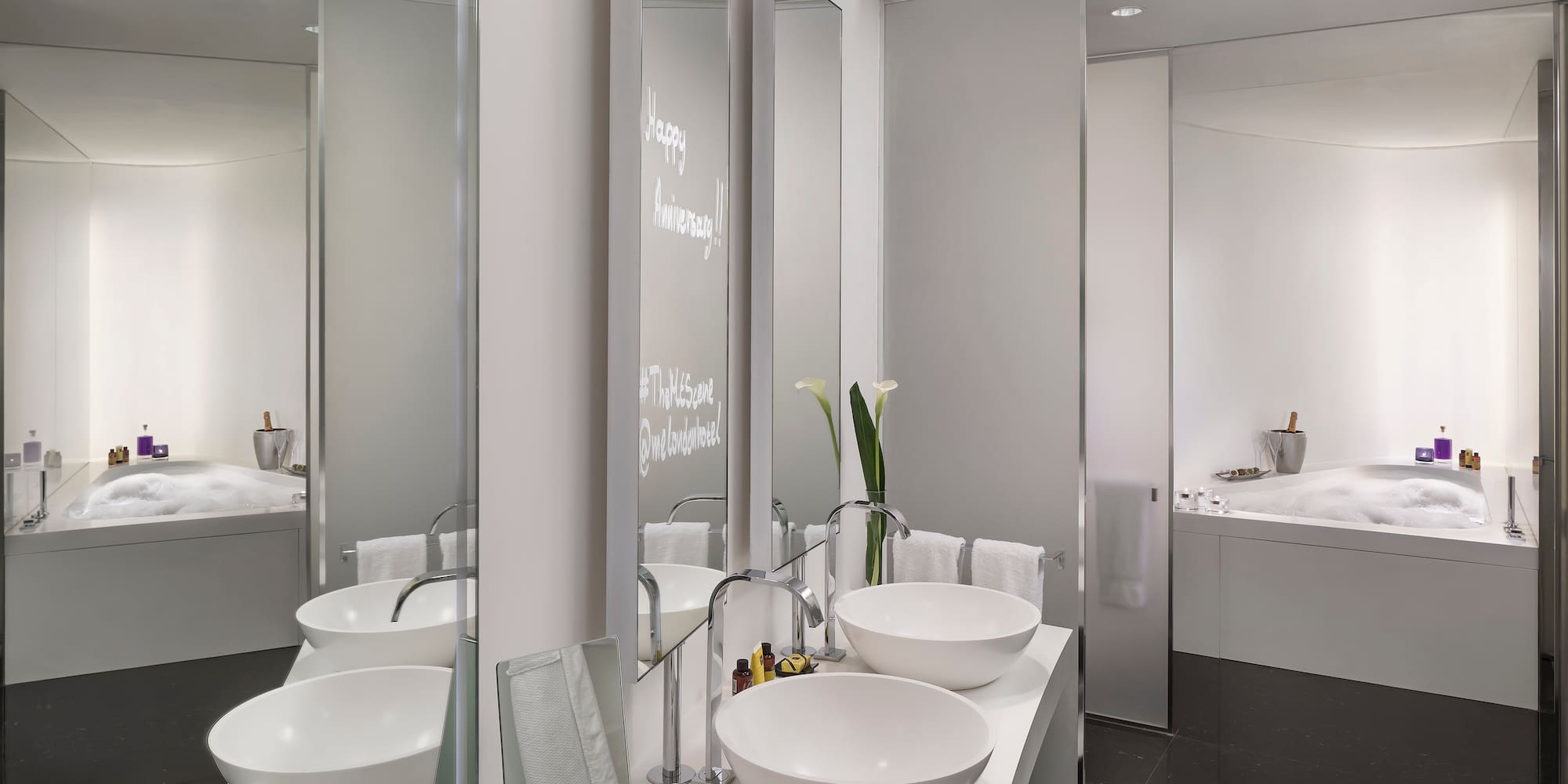 Sleek modern hotel bathroom with double vanity, bowl sinks, and bubbly bathtub.