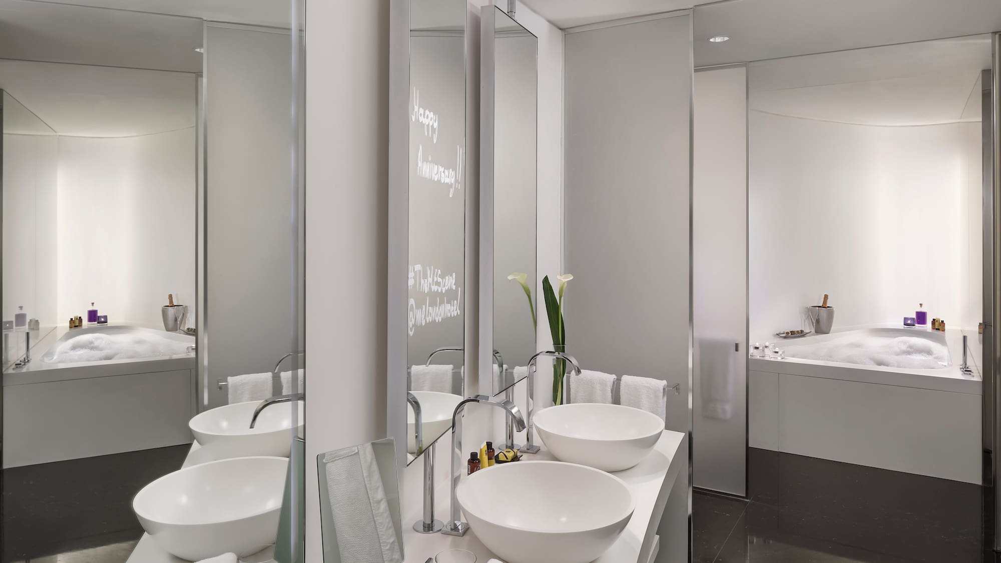 Sleek modern hotel bathroom with double vanity, bowl sinks, and bubbly bathtub.