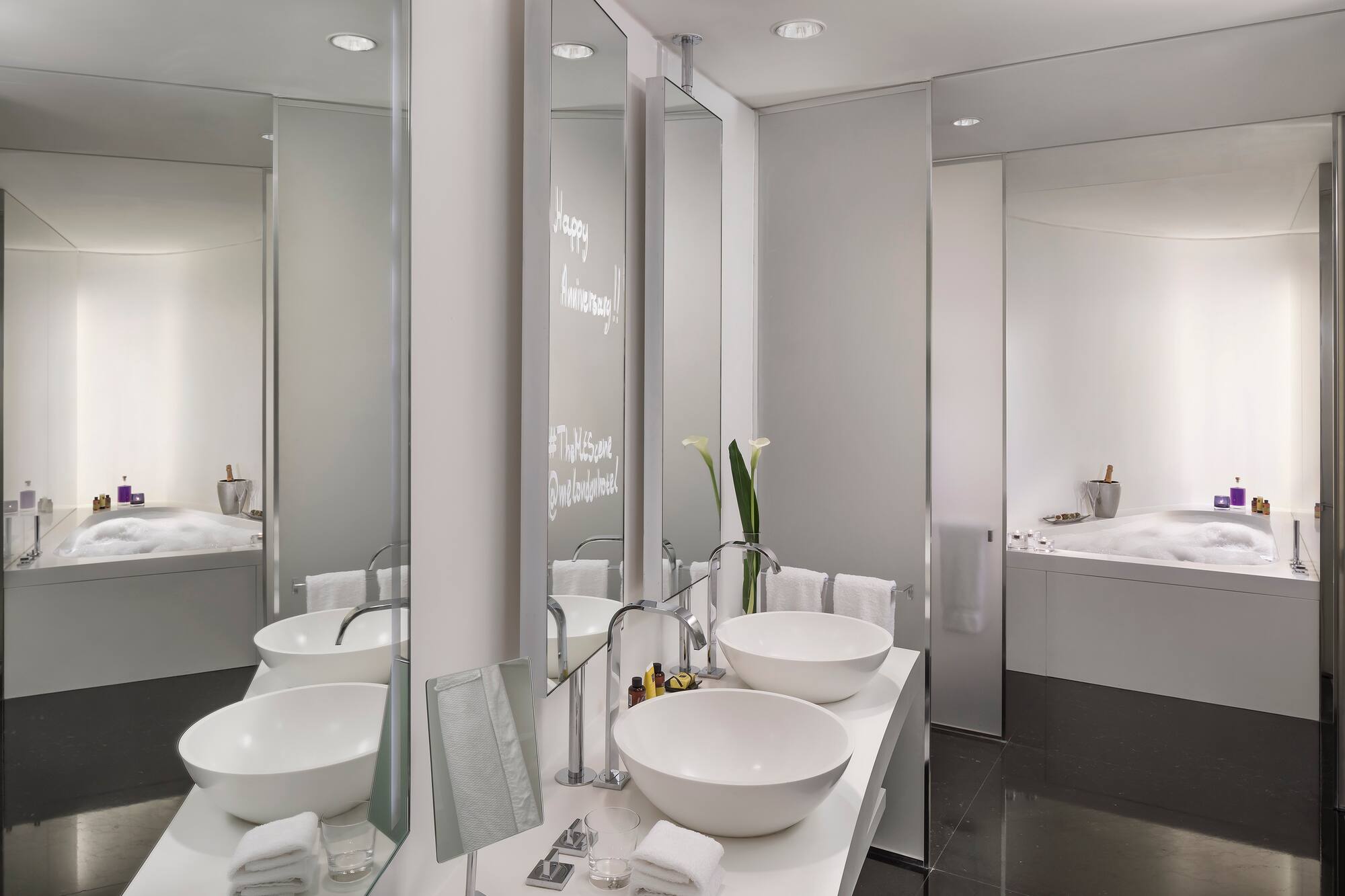 Sleek modern hotel bathroom with double vanity, bowl sinks, and bubbly bathtub.