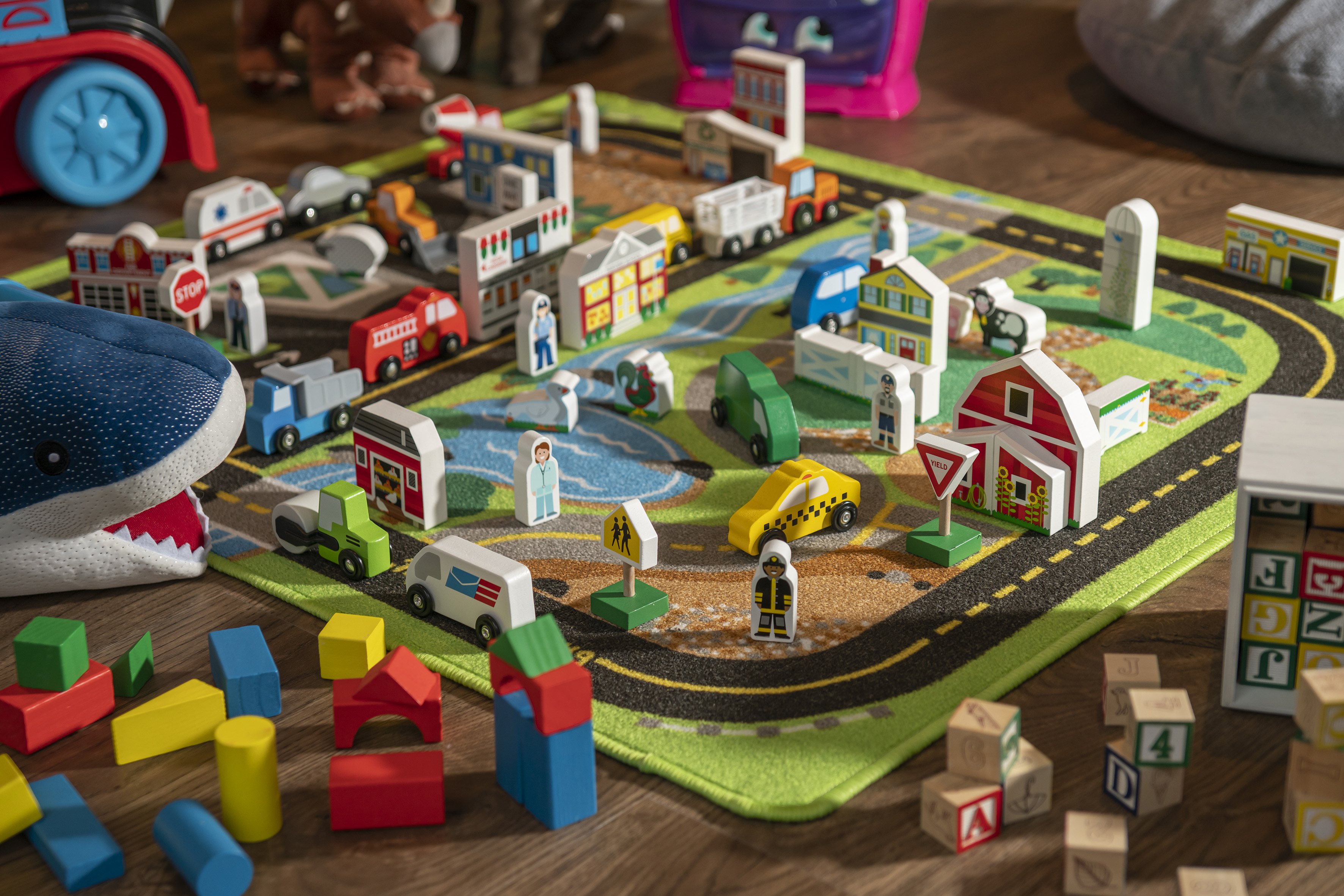 Kids' wooden toy city play mat with cars, buildings, blocks, and figures.