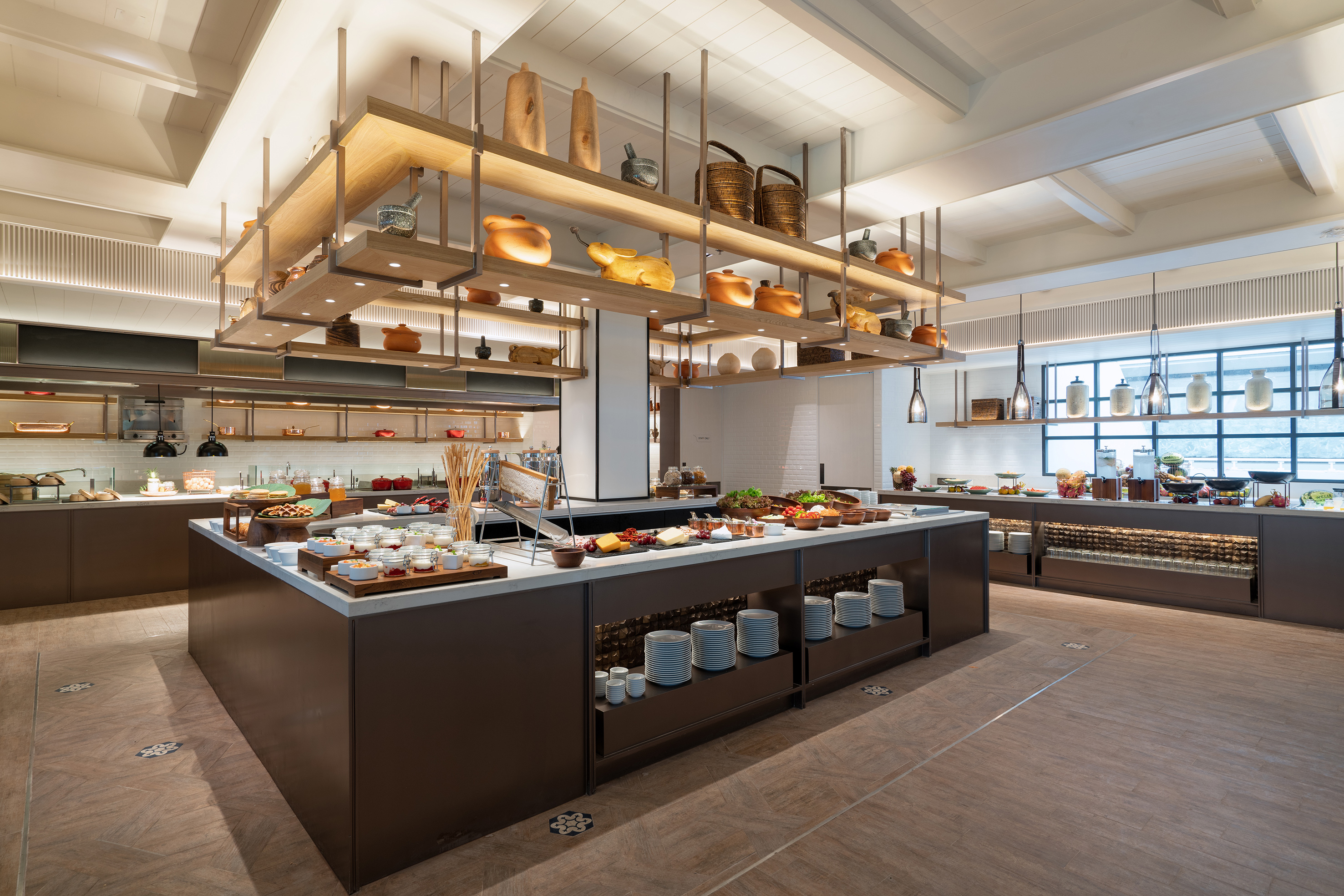 Modern hotel buffet with diverse food stations and stylish overhead decor.