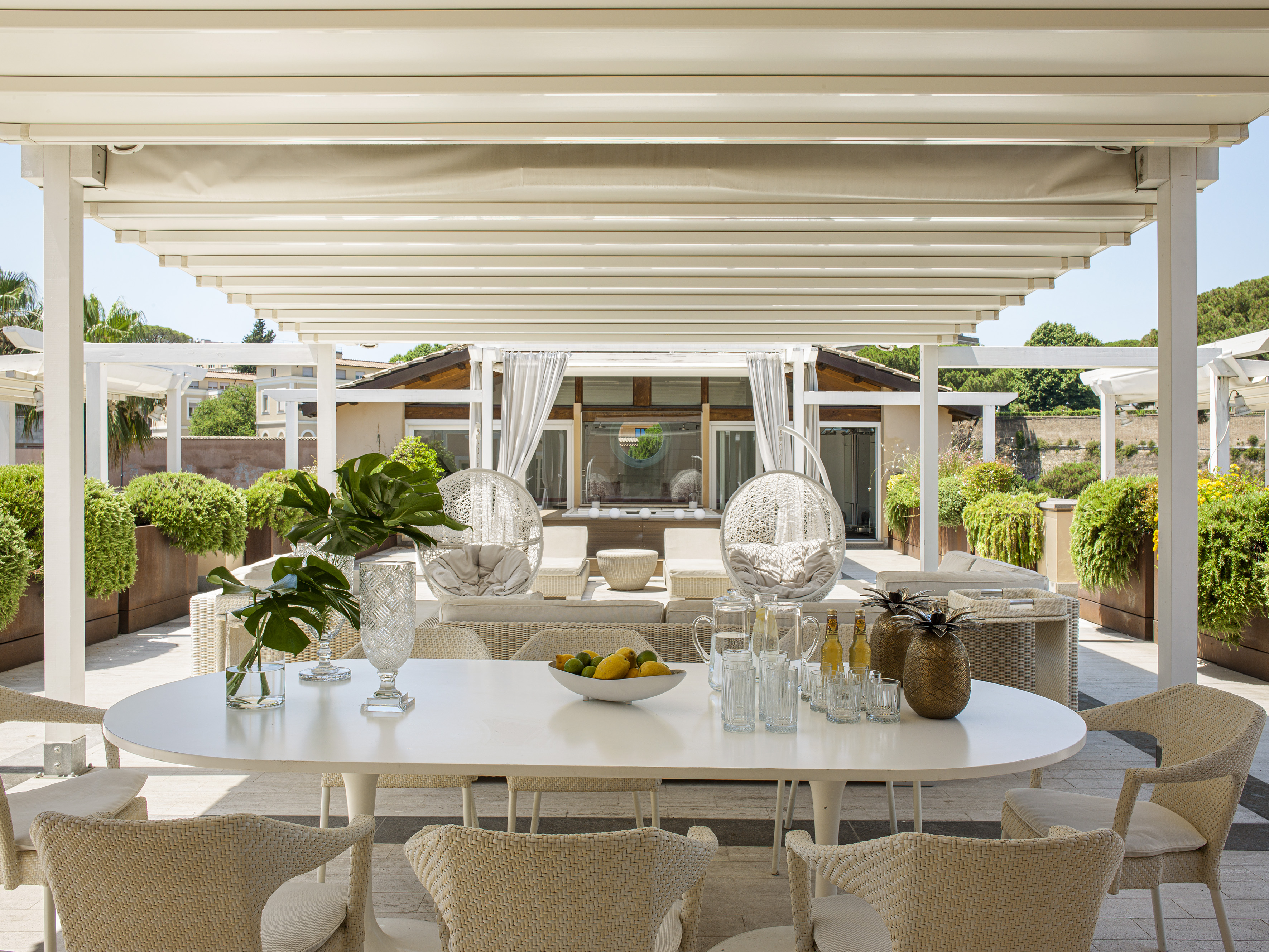 Modern rooftop terrace with retractable pergola, dining table, and lounge area.