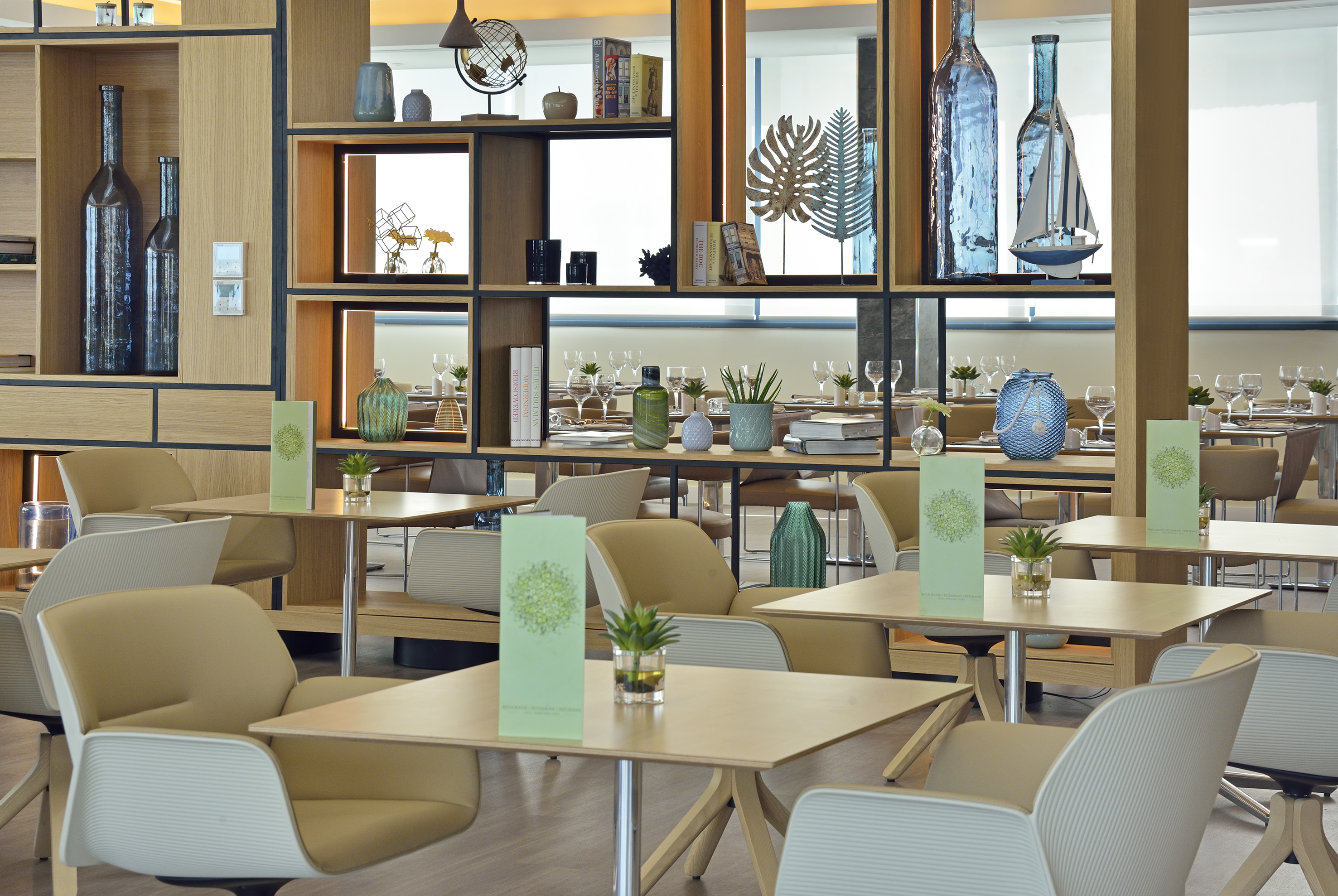 Stylish cafe interior with modern furniture, beige chairs, and decorative wooden shelving.