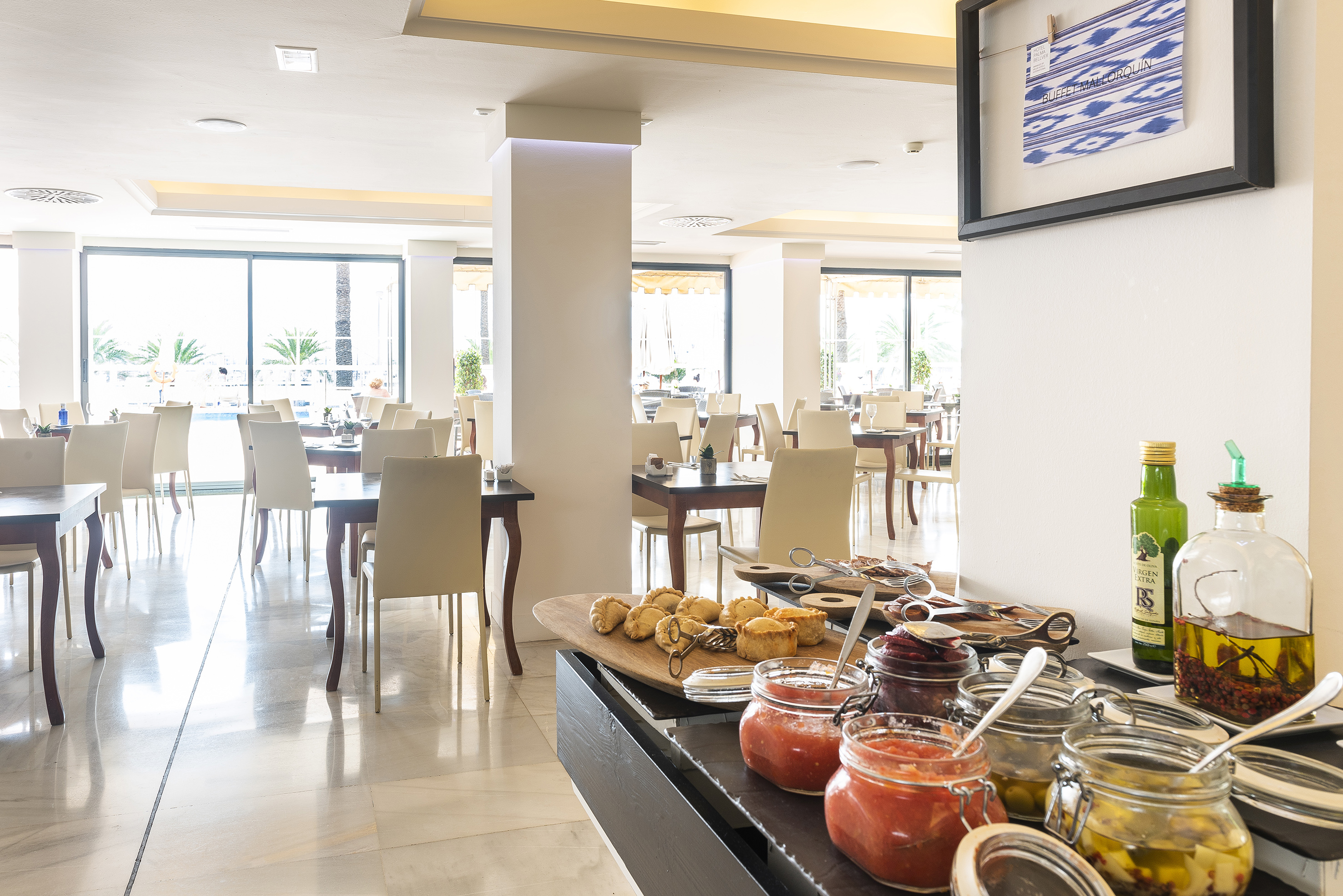 Mallorquín buffet in bright hotel restaurant with pastries, sauces, and dining tables.