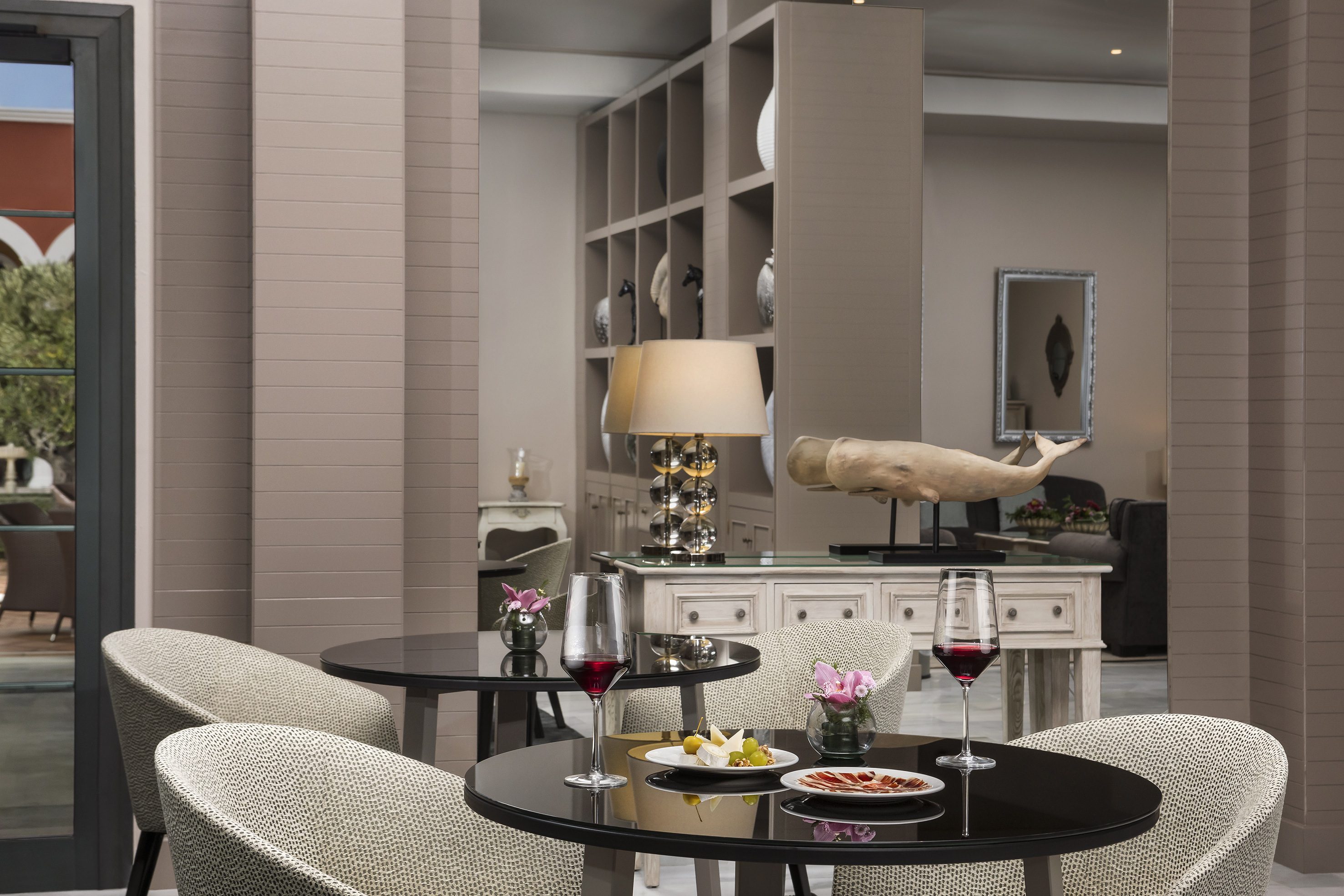 Elegant hotel lounge with black tables, red wine, and appetizers.