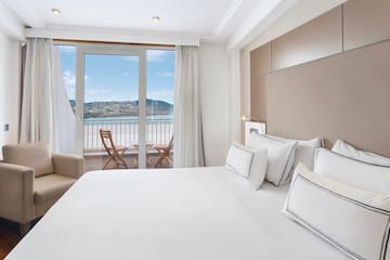 a bed with white sheets and pillows in a hotel room