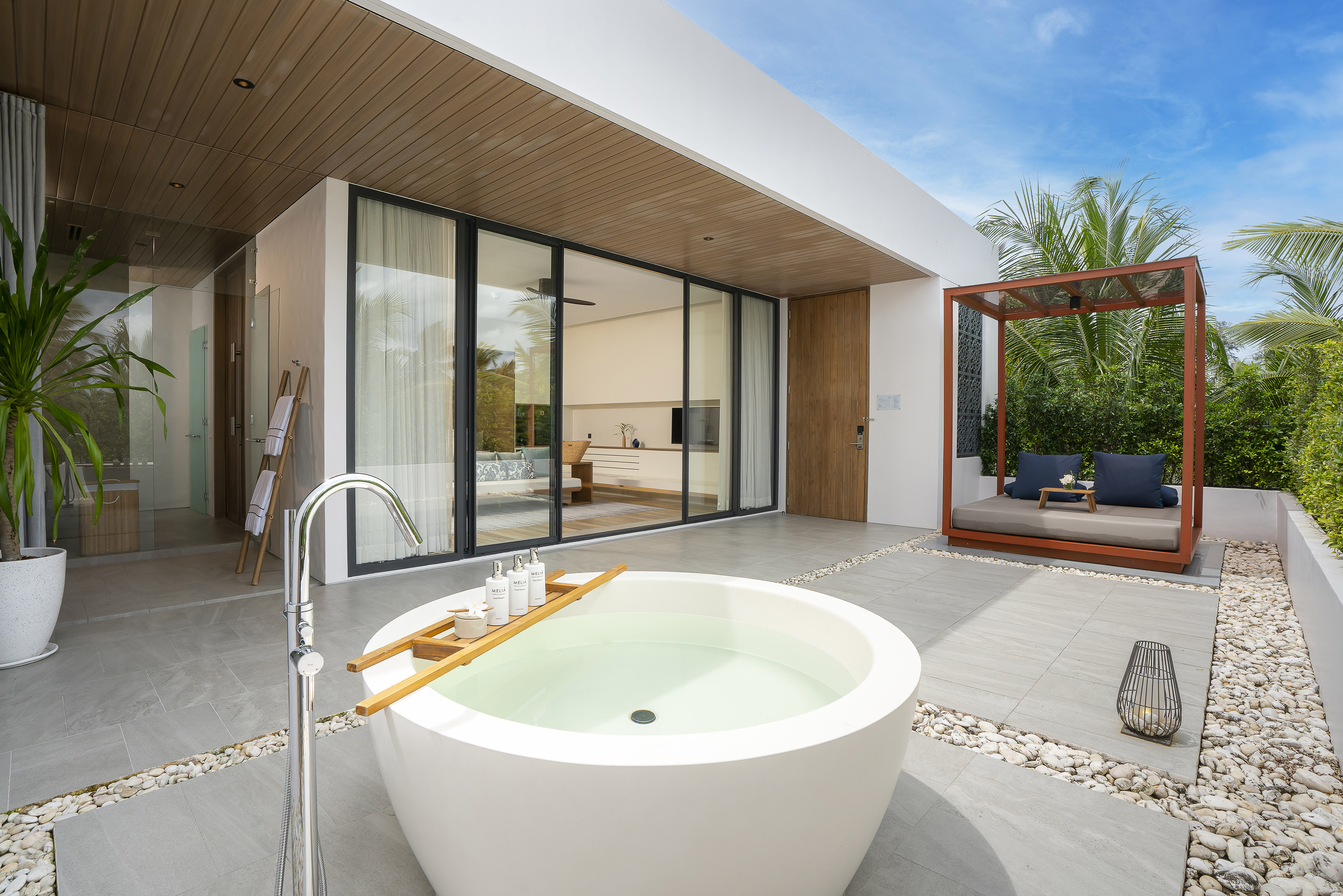 Relaxing outdoor bathtub on a modern villa patio with daybed.