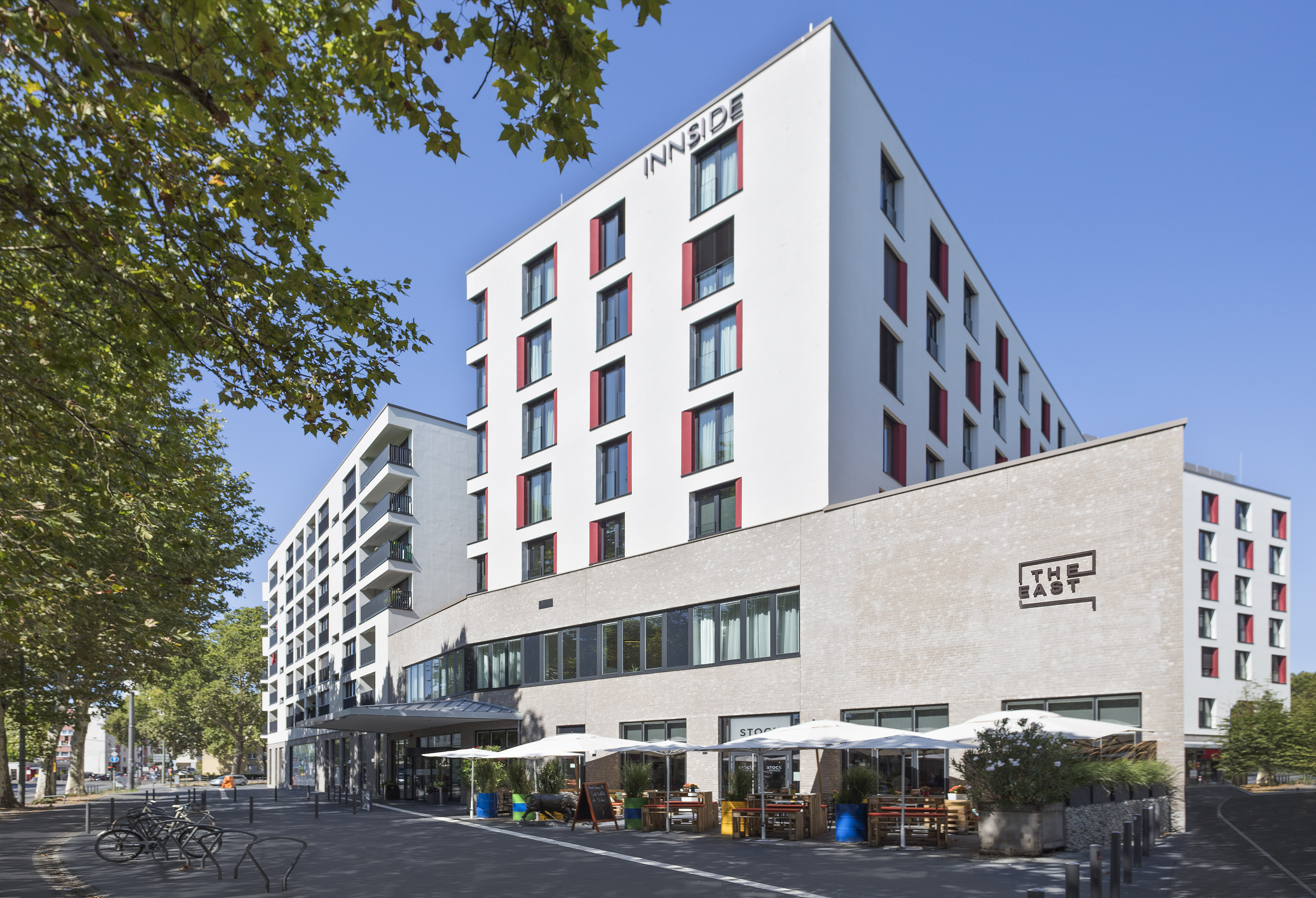 Modern INNSIDE hotel building with THE EAST restaurant and outdoor cafe.