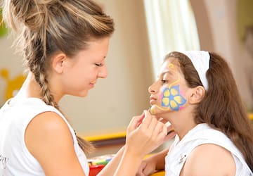 a woman painting a girl's face