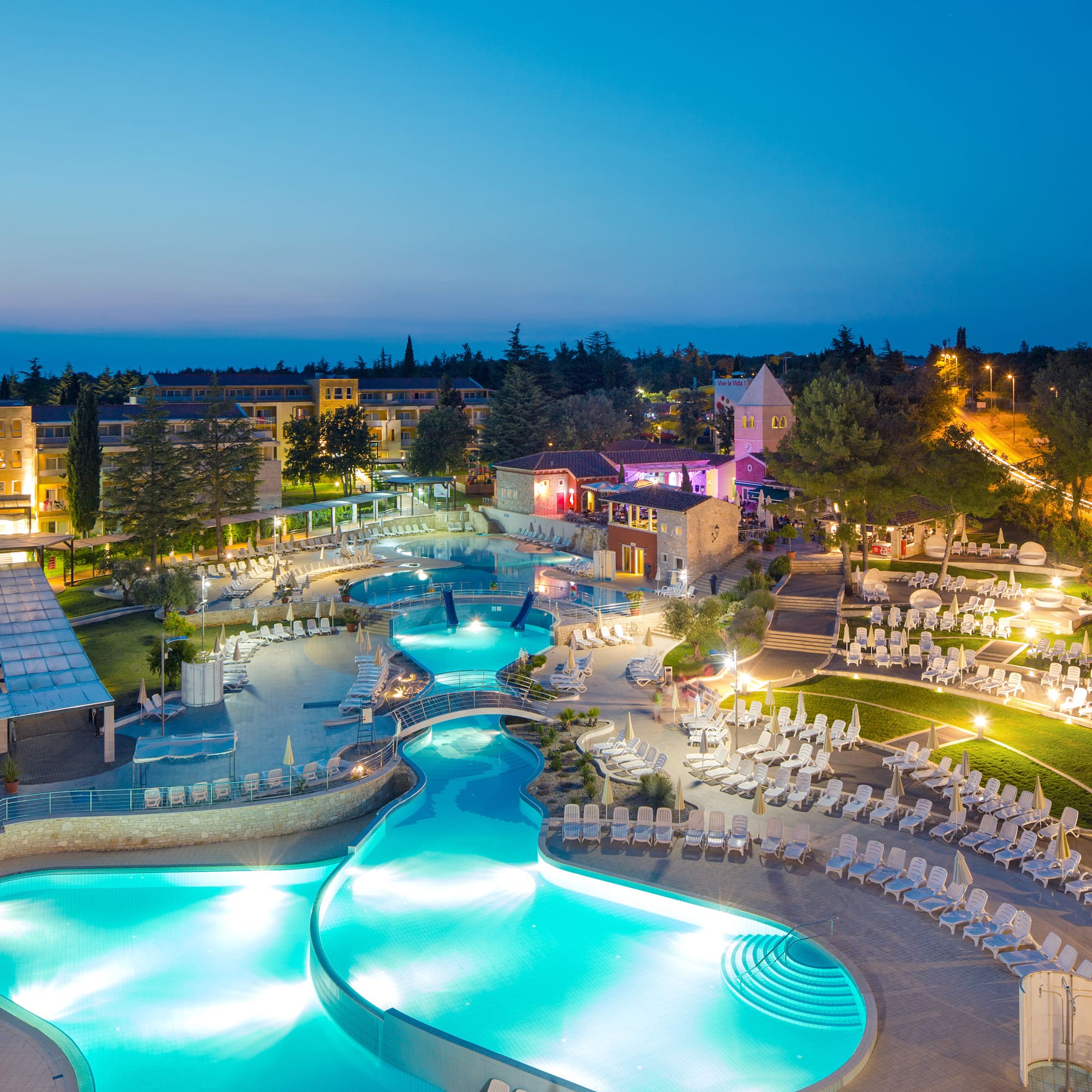 a pool with chairs and a building in the background