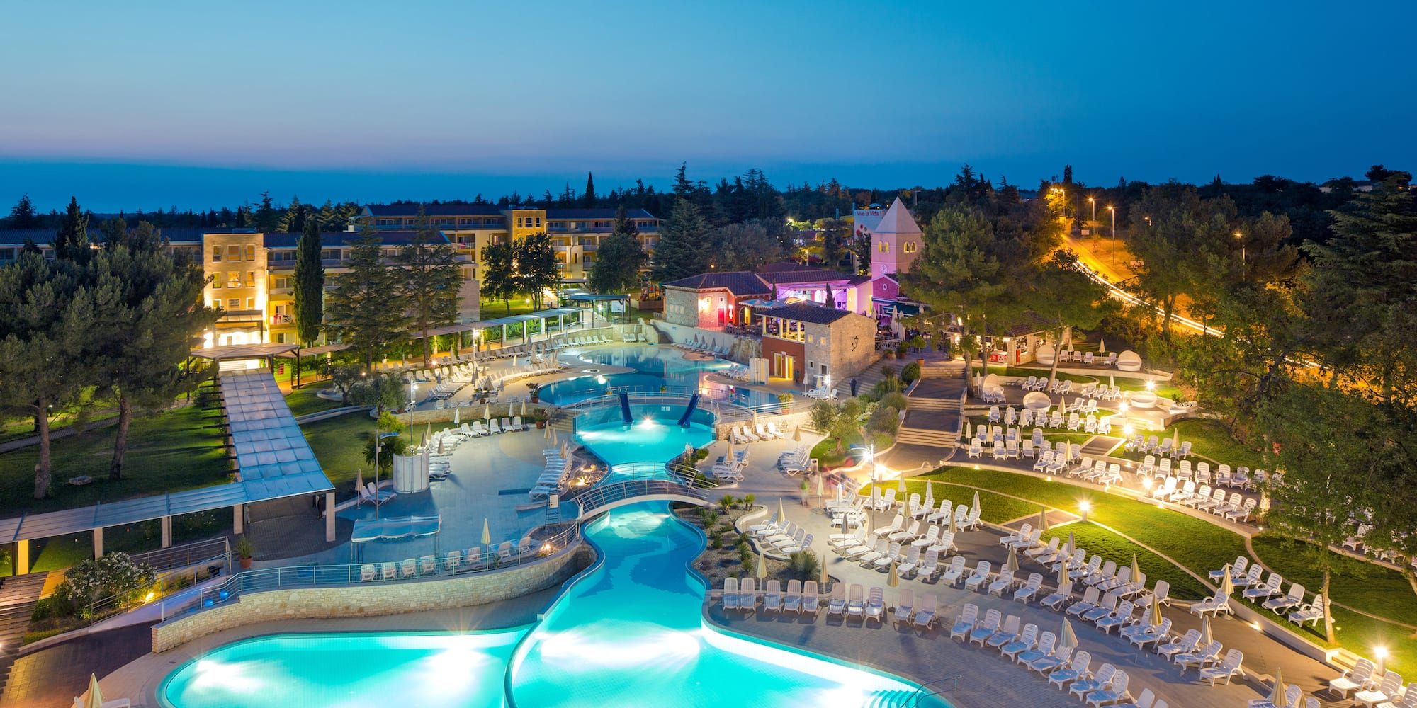 a pool with chairs and a building in the background