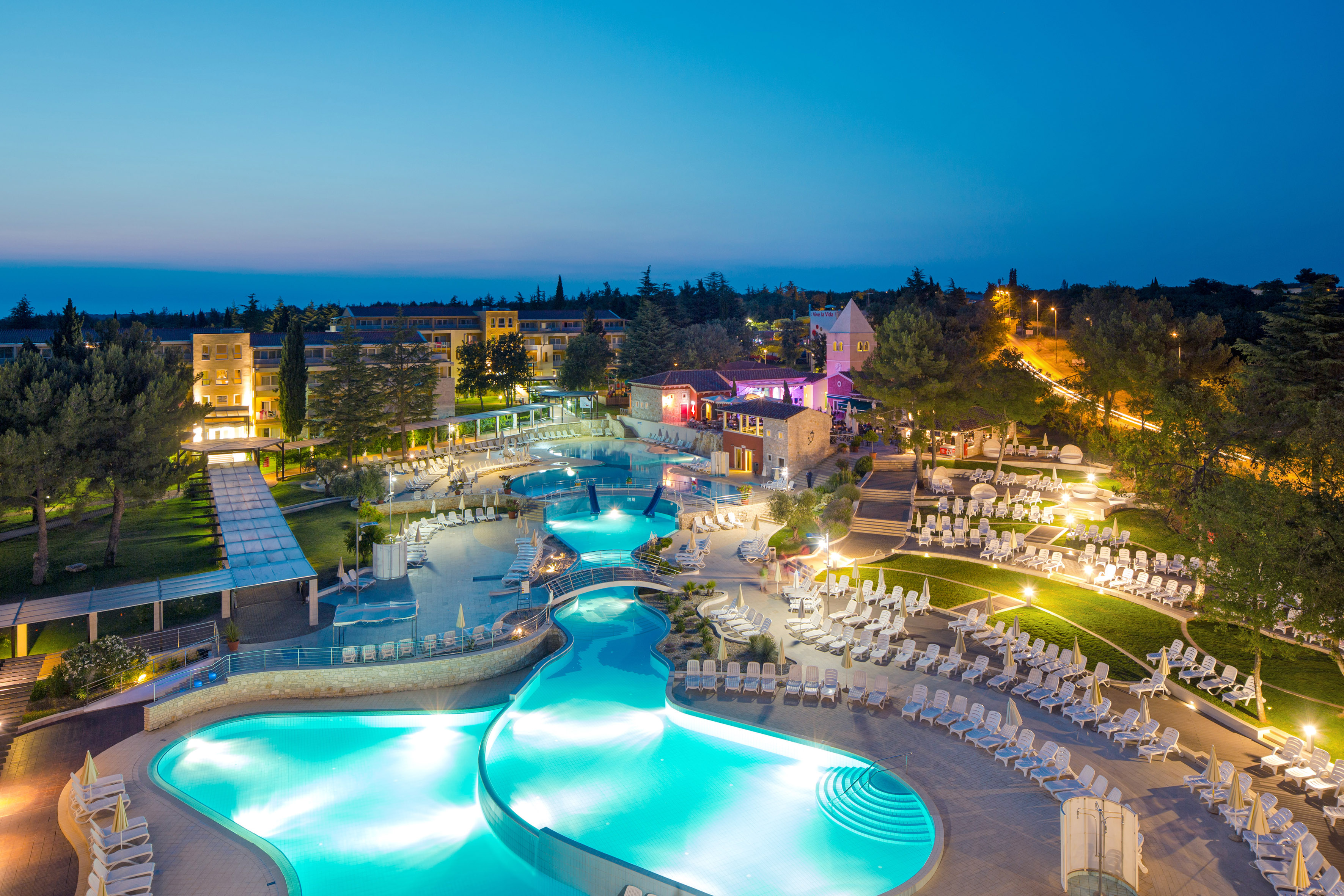 a pool with chairs and a building in the background