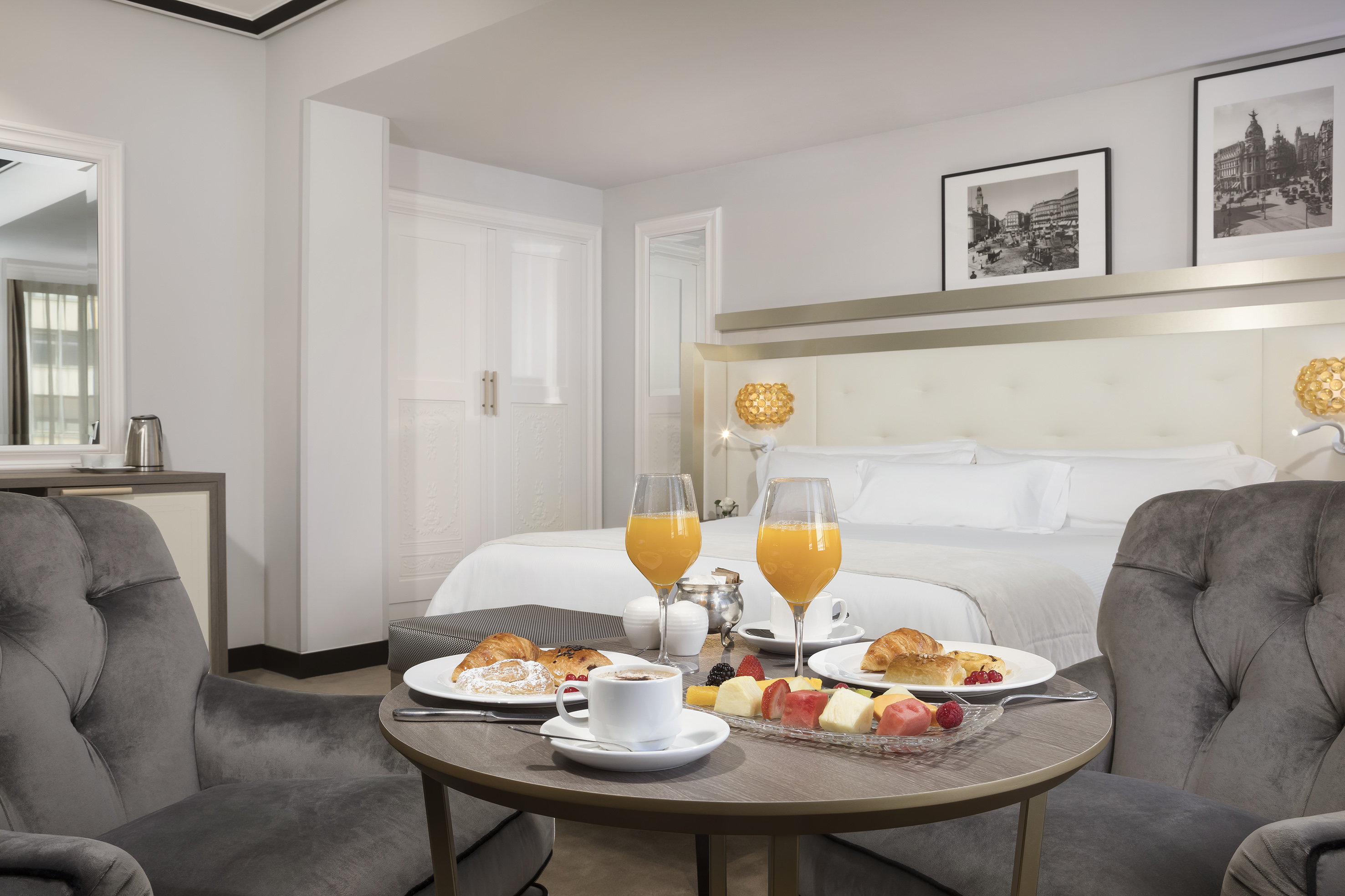 Elegant hotel room breakfast with croissants, fruit, orange juice, coffee.