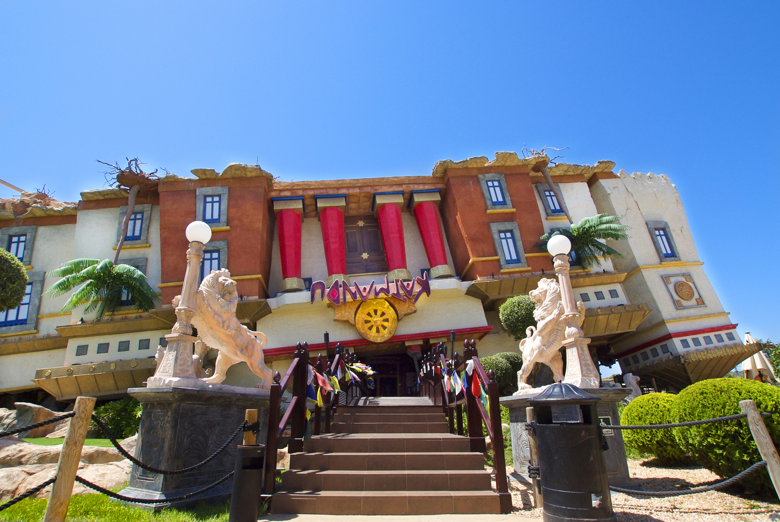 Upside-down Katmandu Park house with red pillars, lion statues, and blue sky.