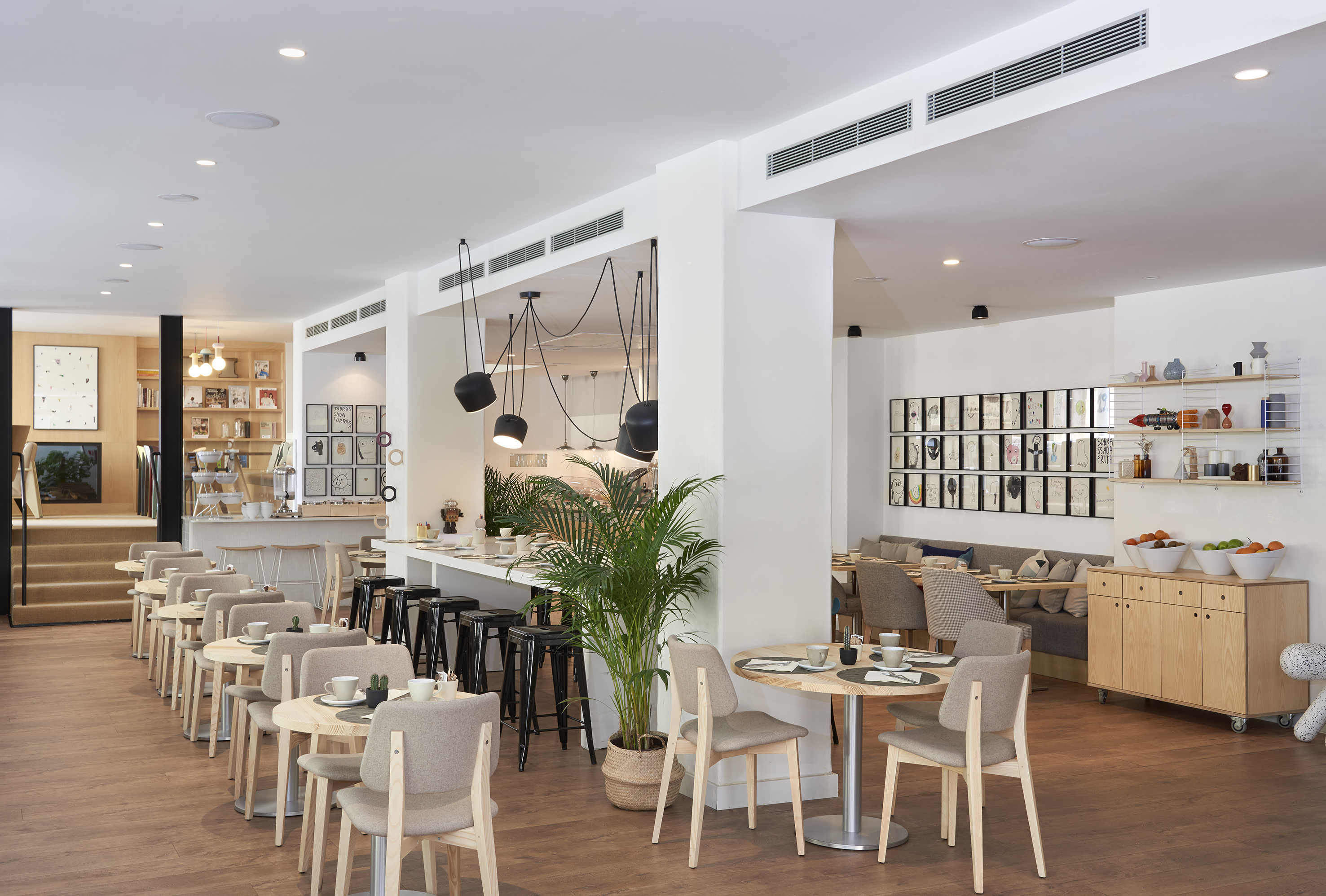 Modern hotel dining area with round wooden tables, bar, and stylish interior.