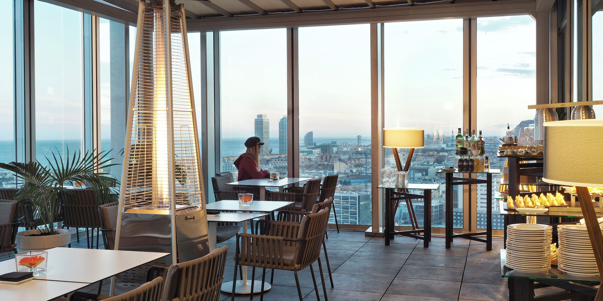 a room with a large window and a woman sitting at a table