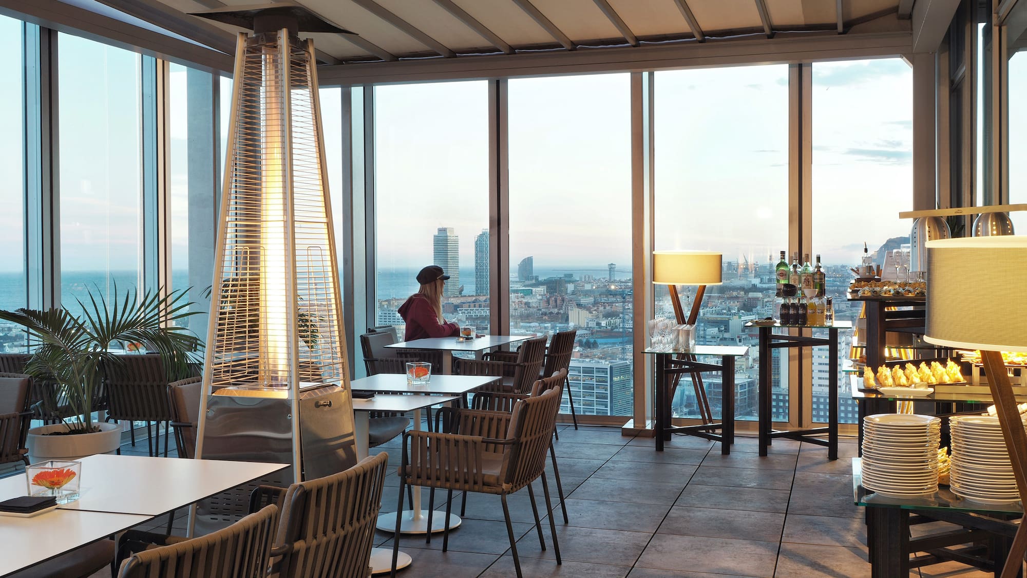 a room with a large window and a woman sitting at a table