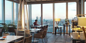 a room with a large window and a woman sitting at a table