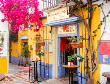a yellow building with a sign and tables and chairs
