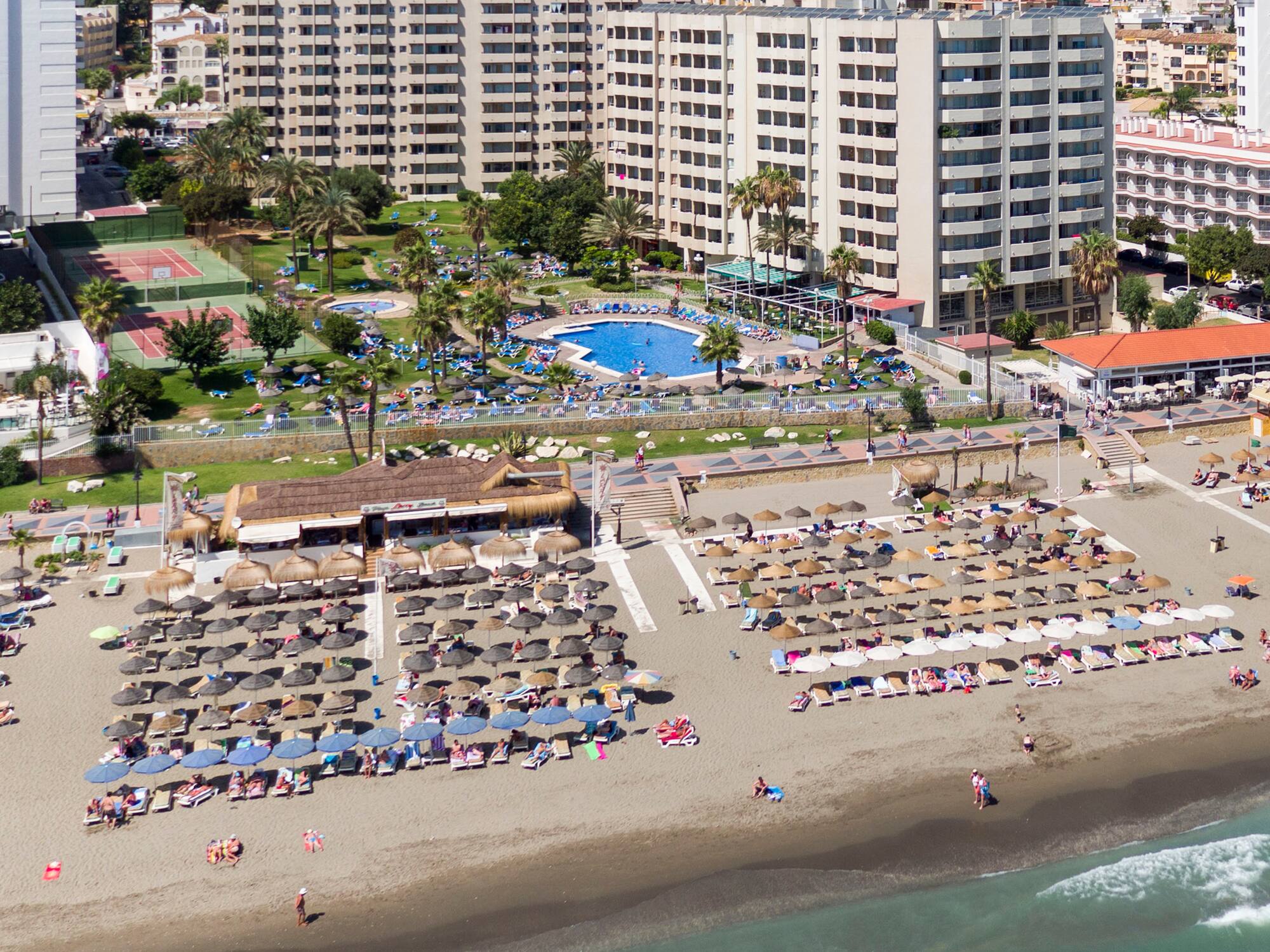 a beach with umbrellas and chairs and a swimming pool