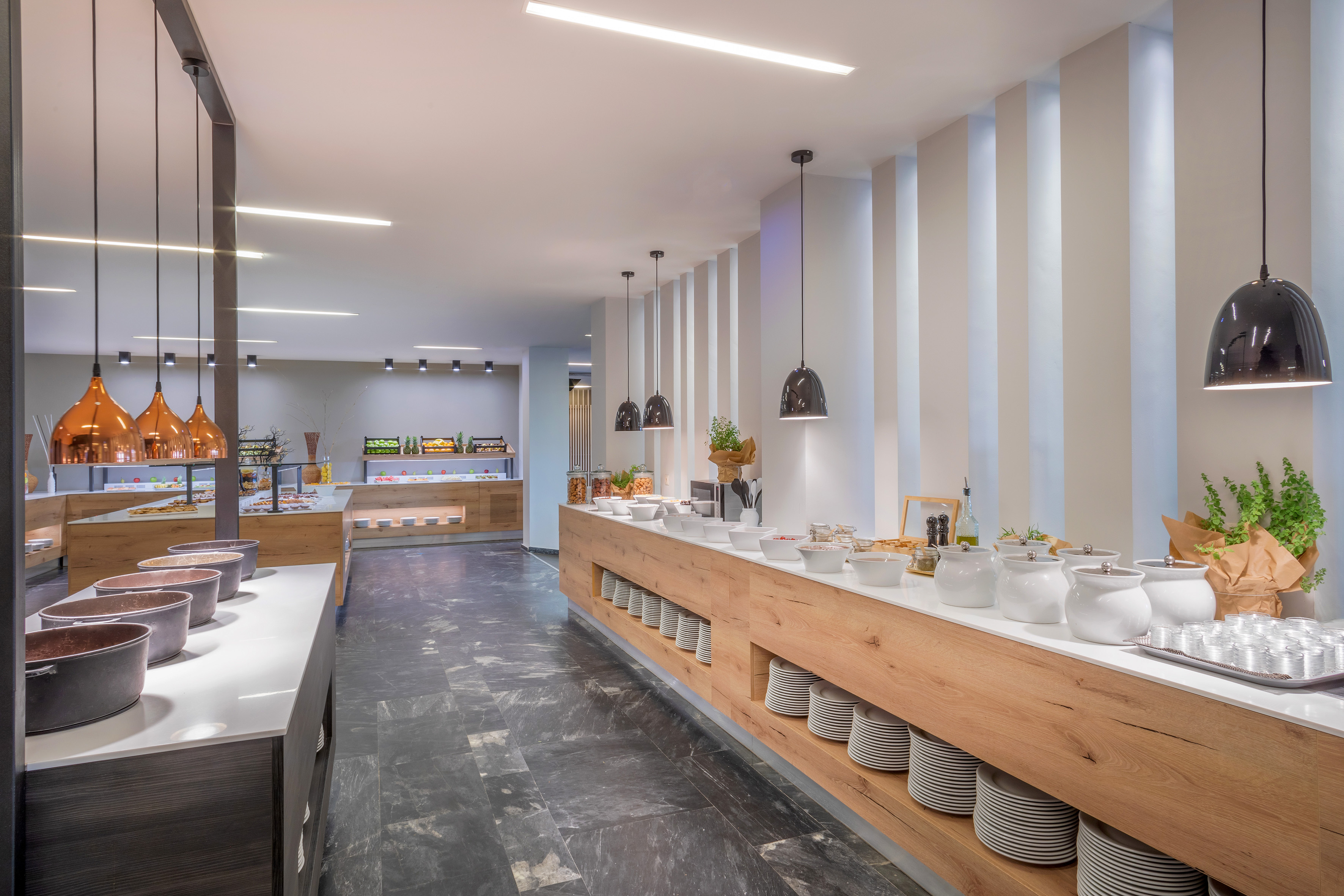 Modern hotel buffet restaurant with food options and stylish pendant lighting.