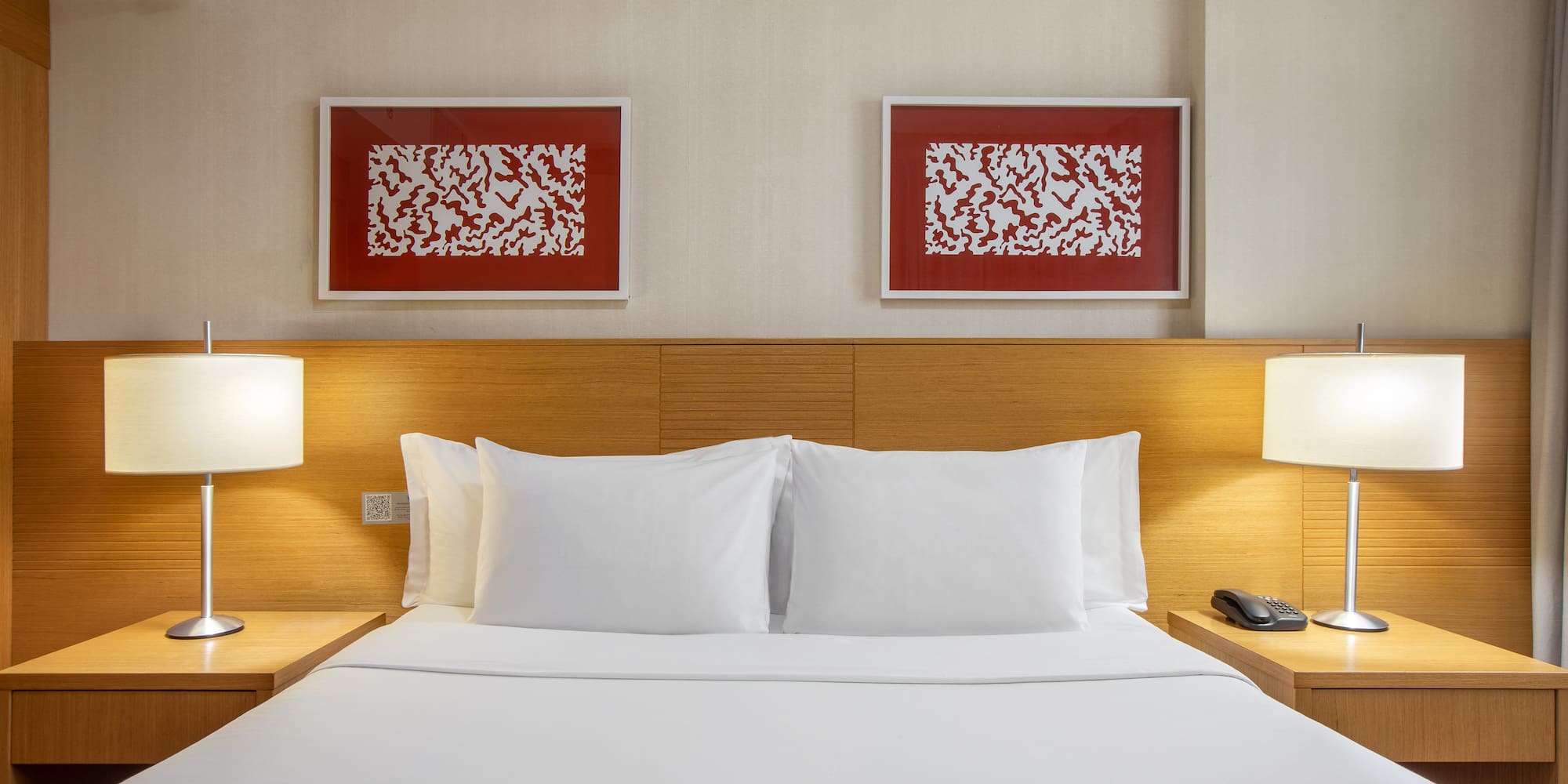 a bed with white sheets and lamps