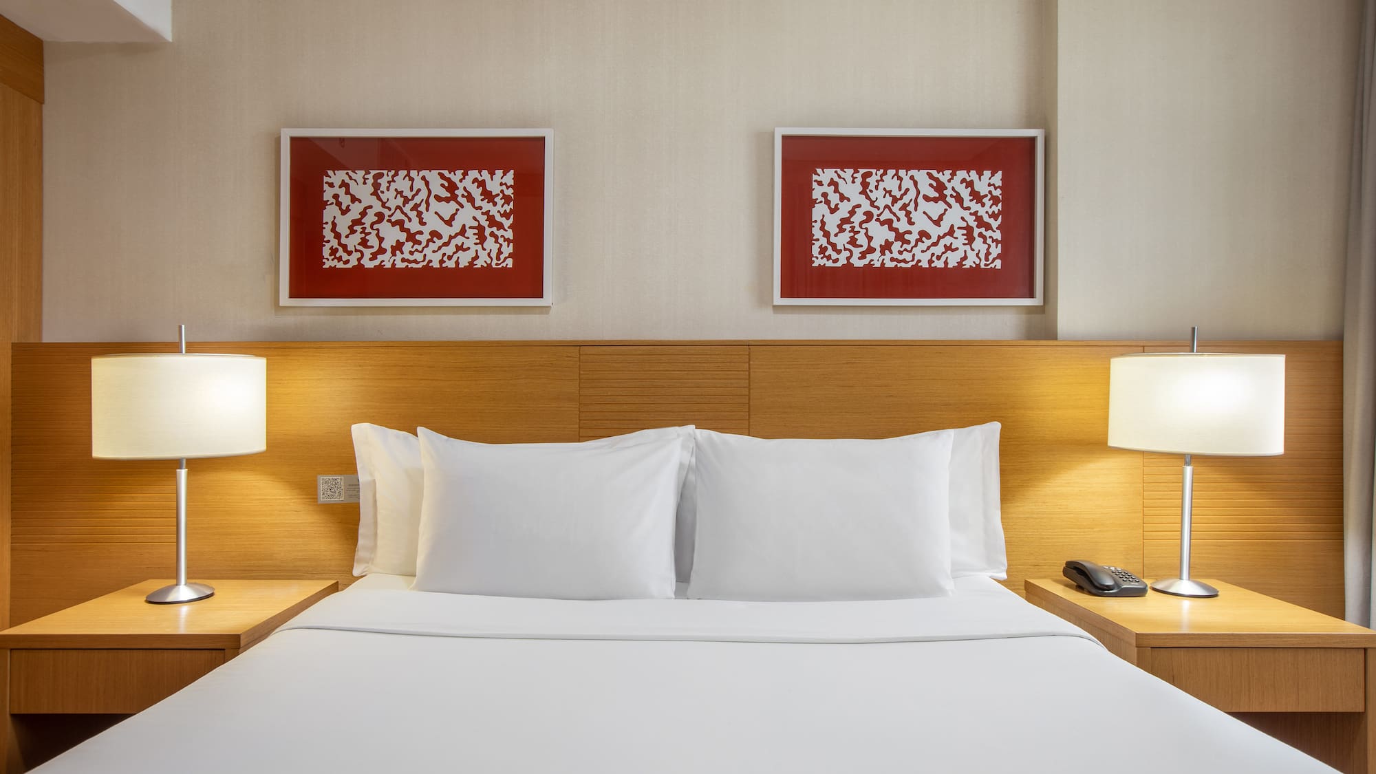 a bed with white sheets and lamps