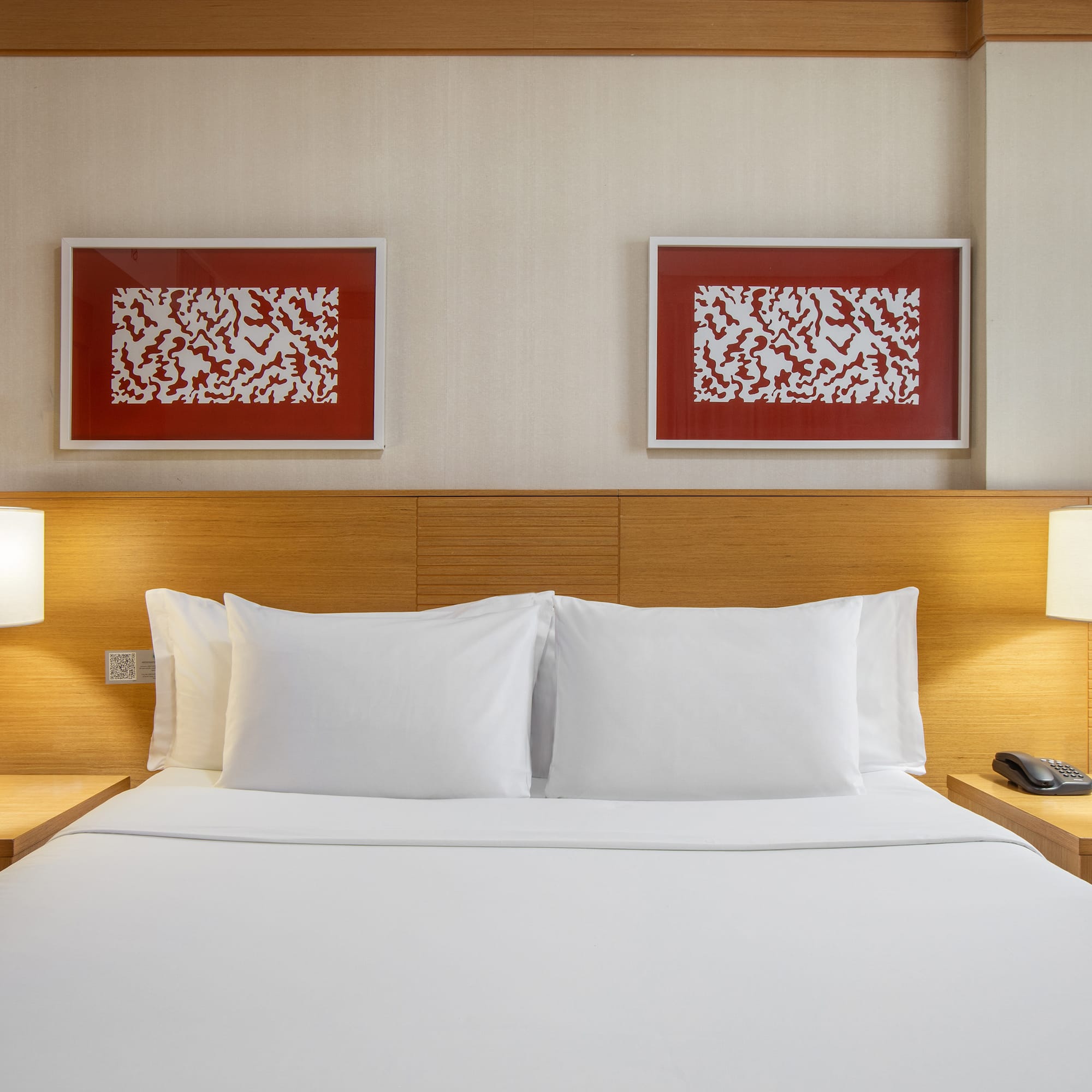 a bed with white sheets and lamps