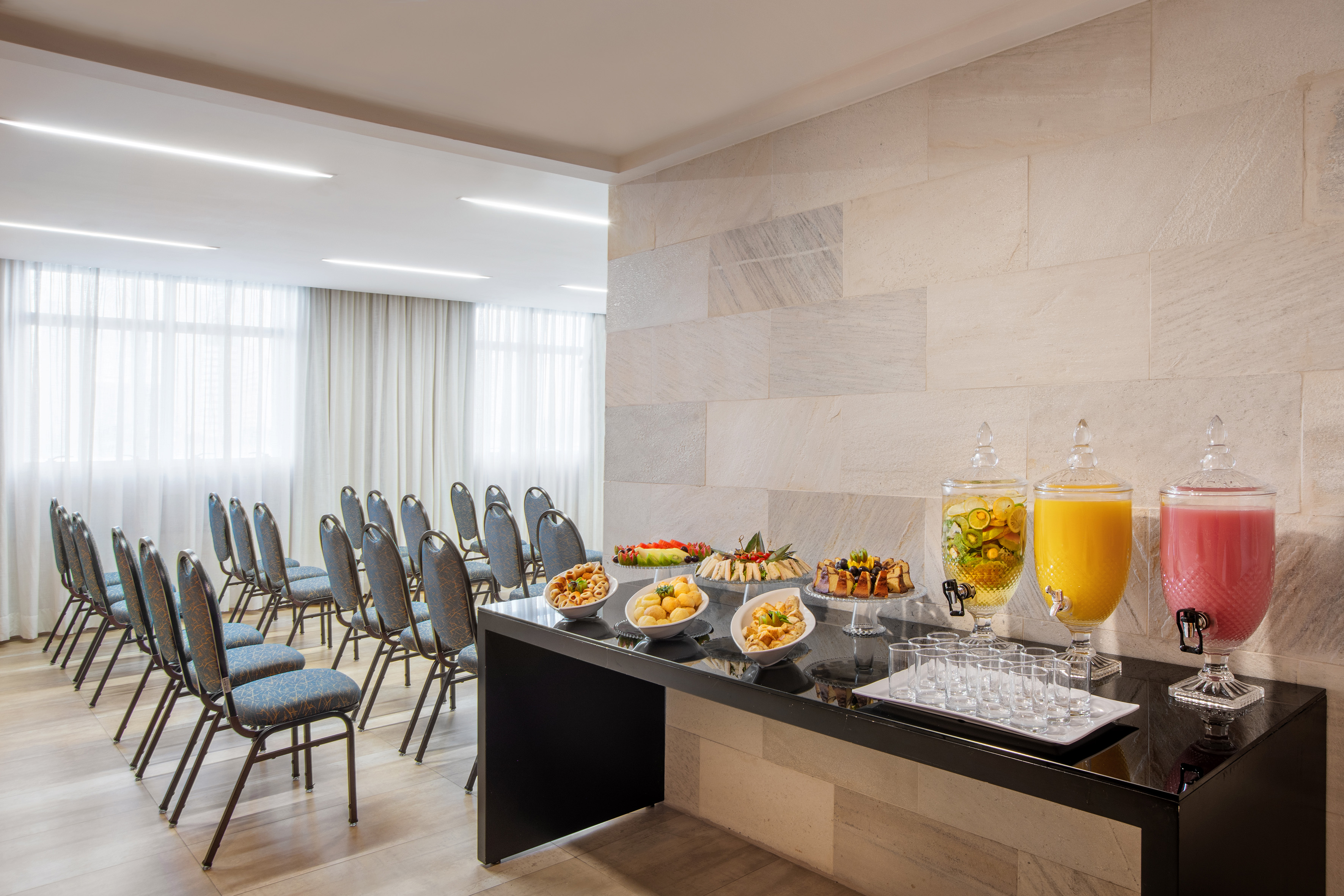 Modern conference room with rows of chairs and a colorful catering buffet.