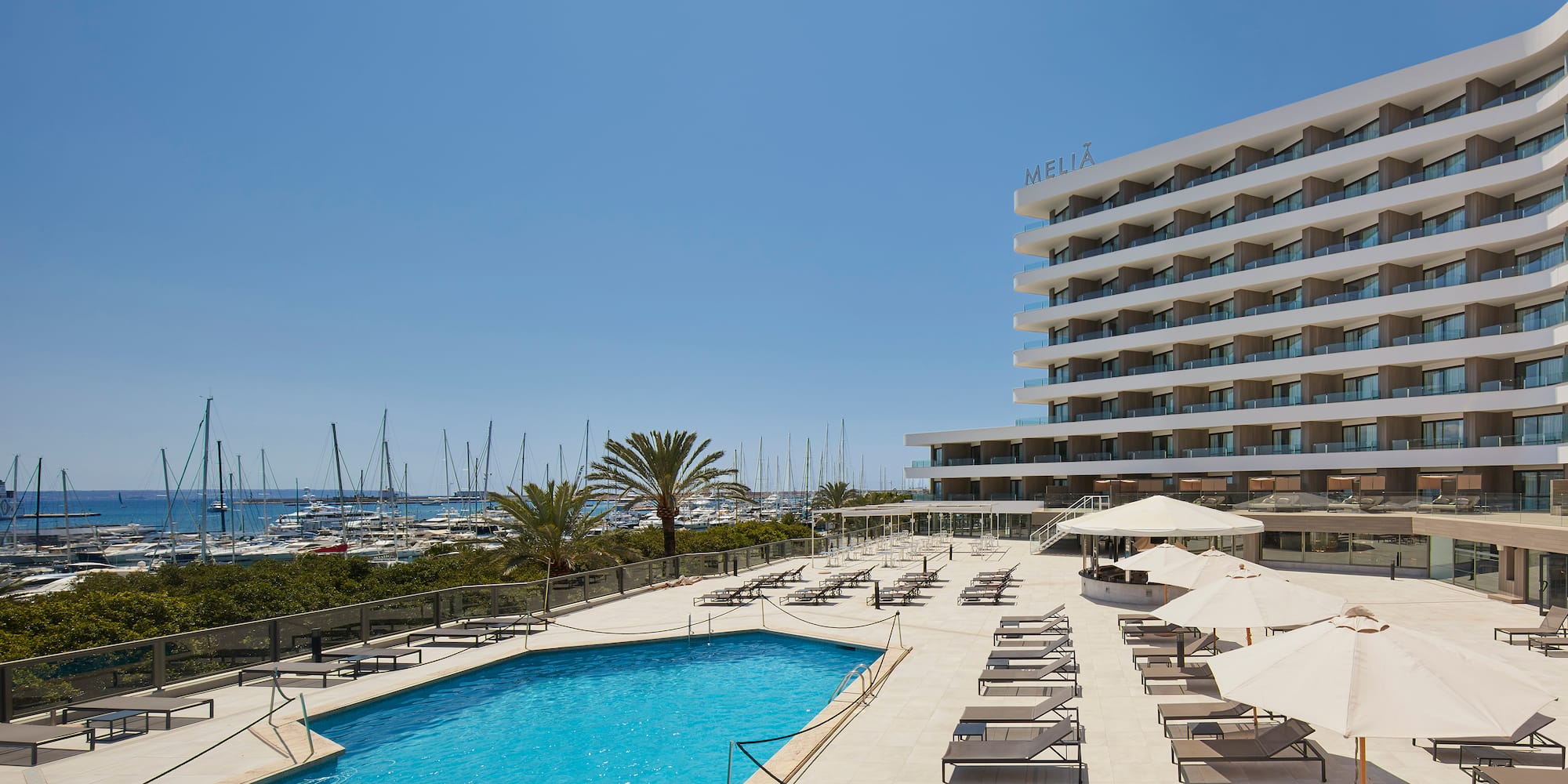 a pool with umbrellas and chairs by a building