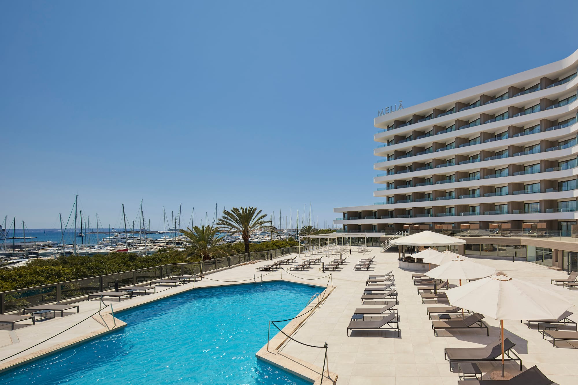 a pool with umbrellas and chairs by a building