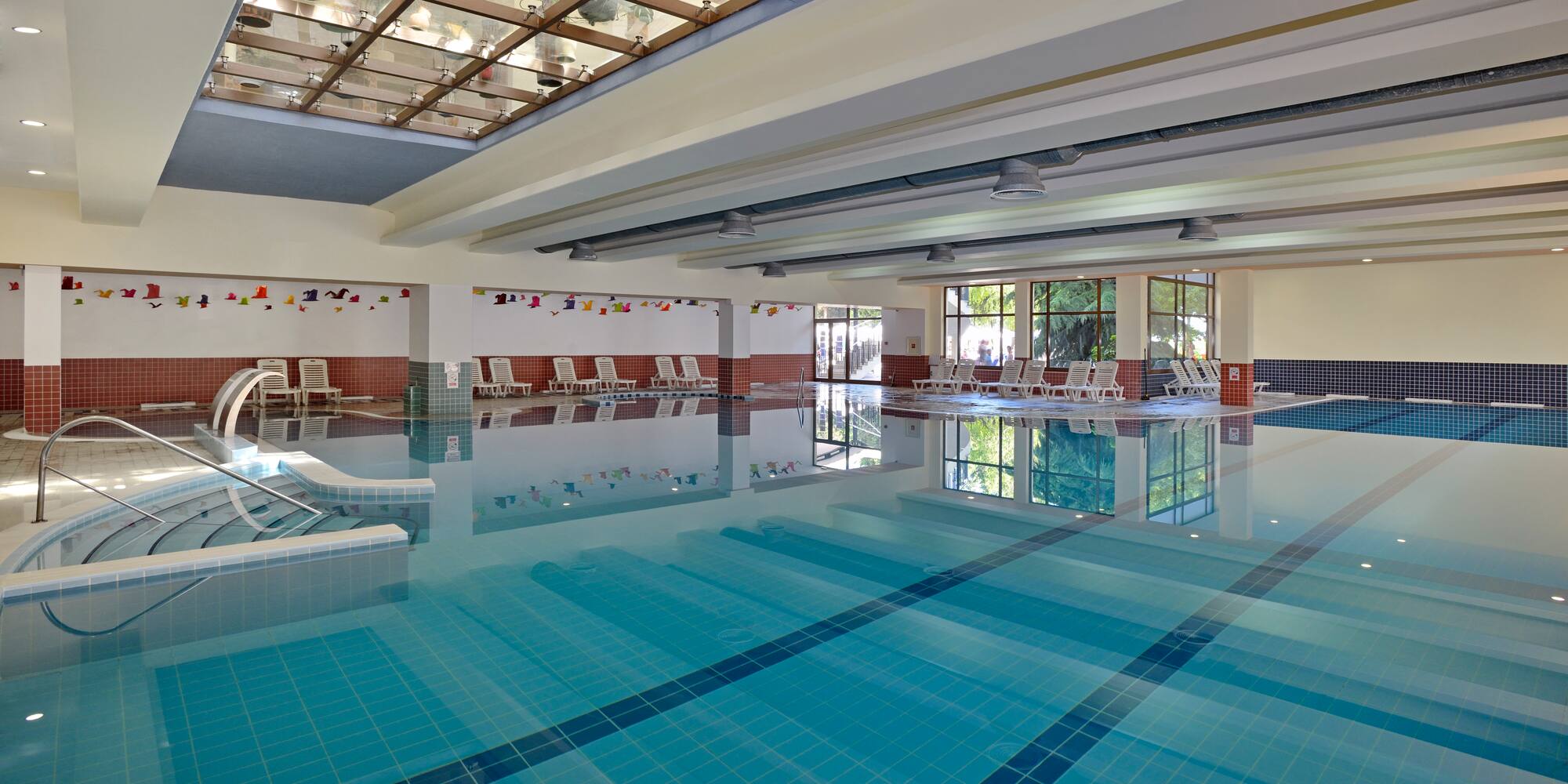 a swimming pool with chairs and a glass ceiling