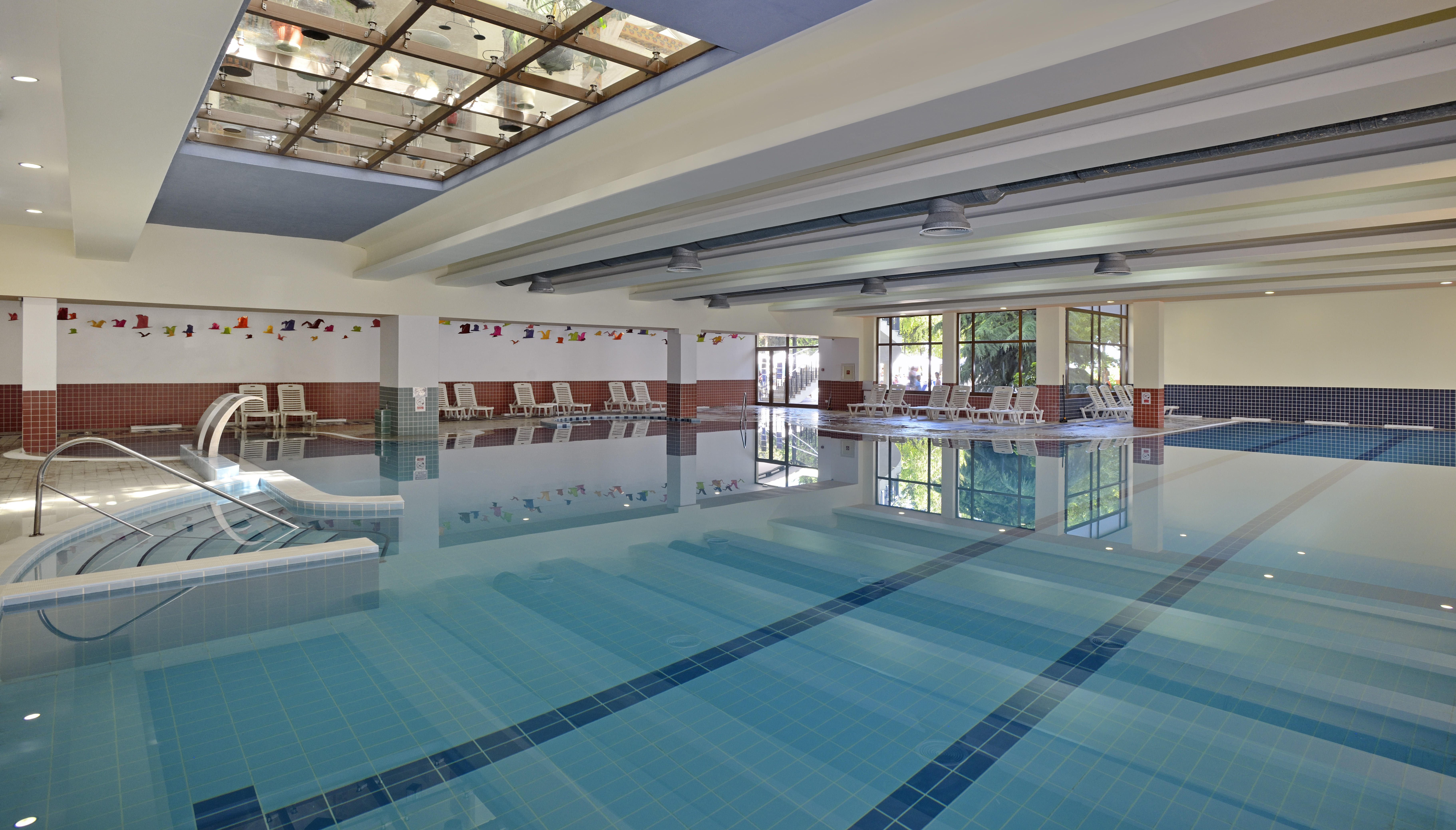 a swimming pool with chairs and a glass ceiling