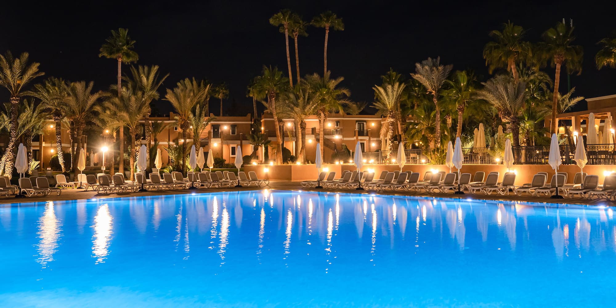 a pool with palm trees and a building in the background