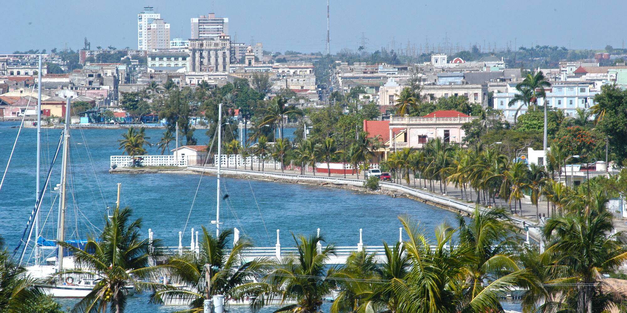 a body of water with palm trees and buildings in the background