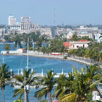 a body of water with palm trees and buildings in the background