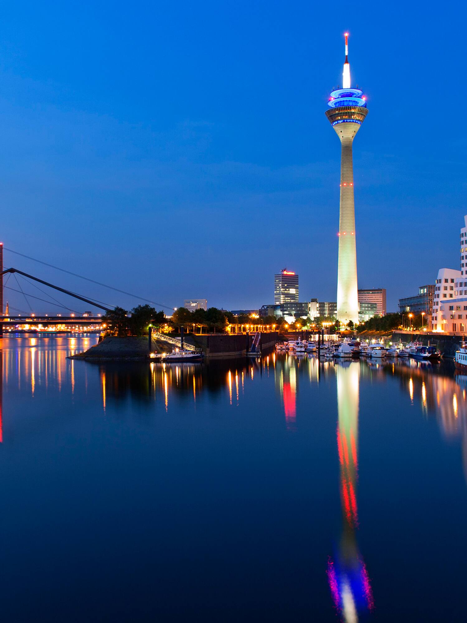 Düsseldorf skyline at dusk with Rheinturm, Rhine River, and modern architecture.