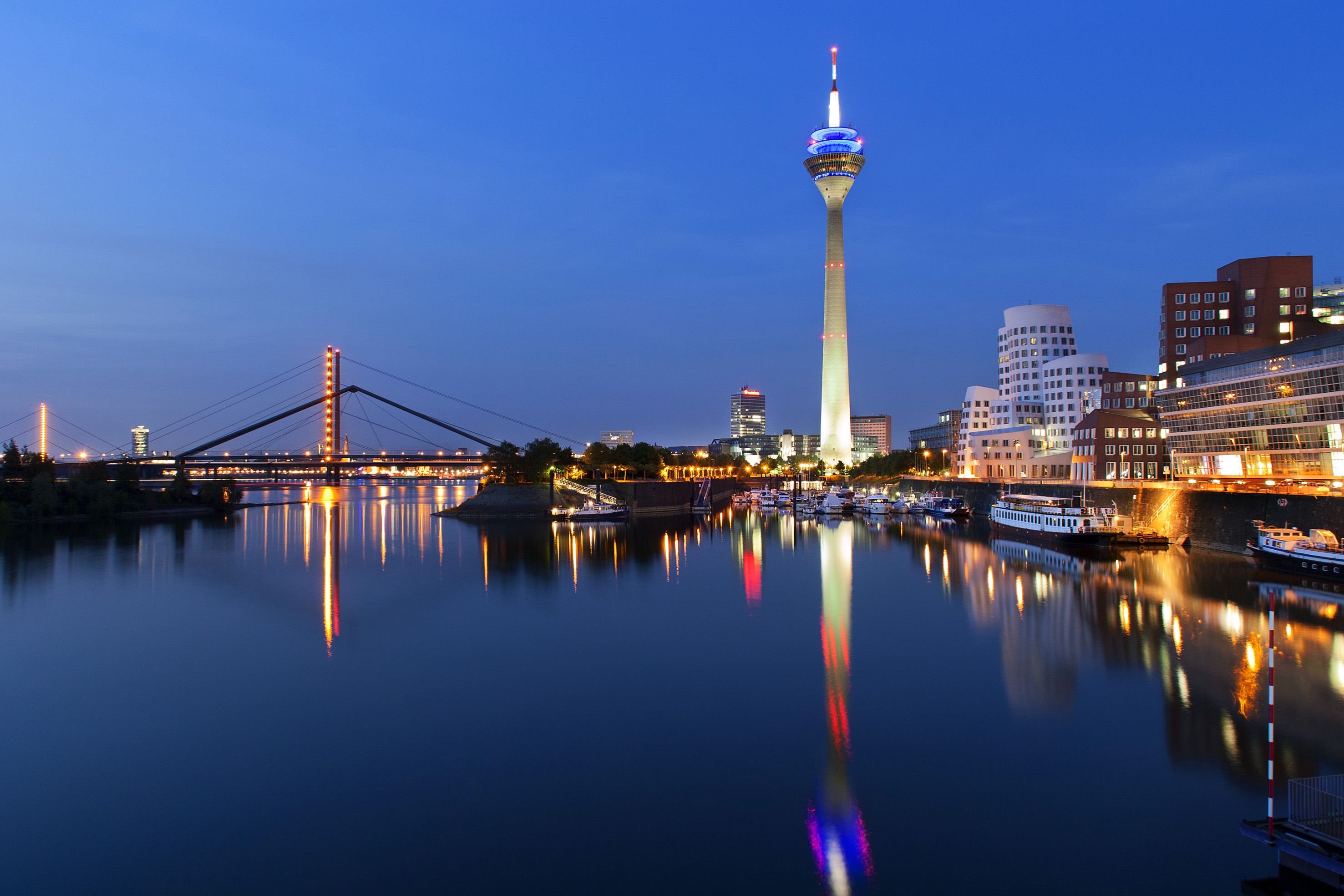 Düsseldorf skyline at dusk with Rheinturm, Rhine River, and modern architecture.