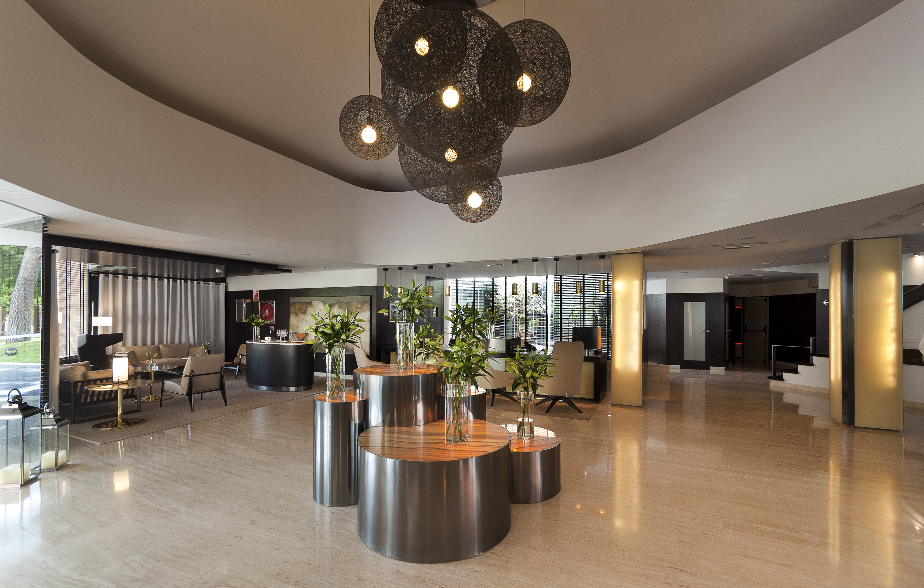 Modern hotel lobby with stylish spherical chandeliers, marble floor, and lounge.