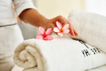 a person's hand holding flowers over a rolled up towel
