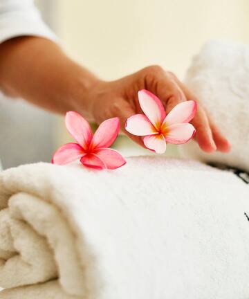 a person's hand holding flowers over a rolled up towel