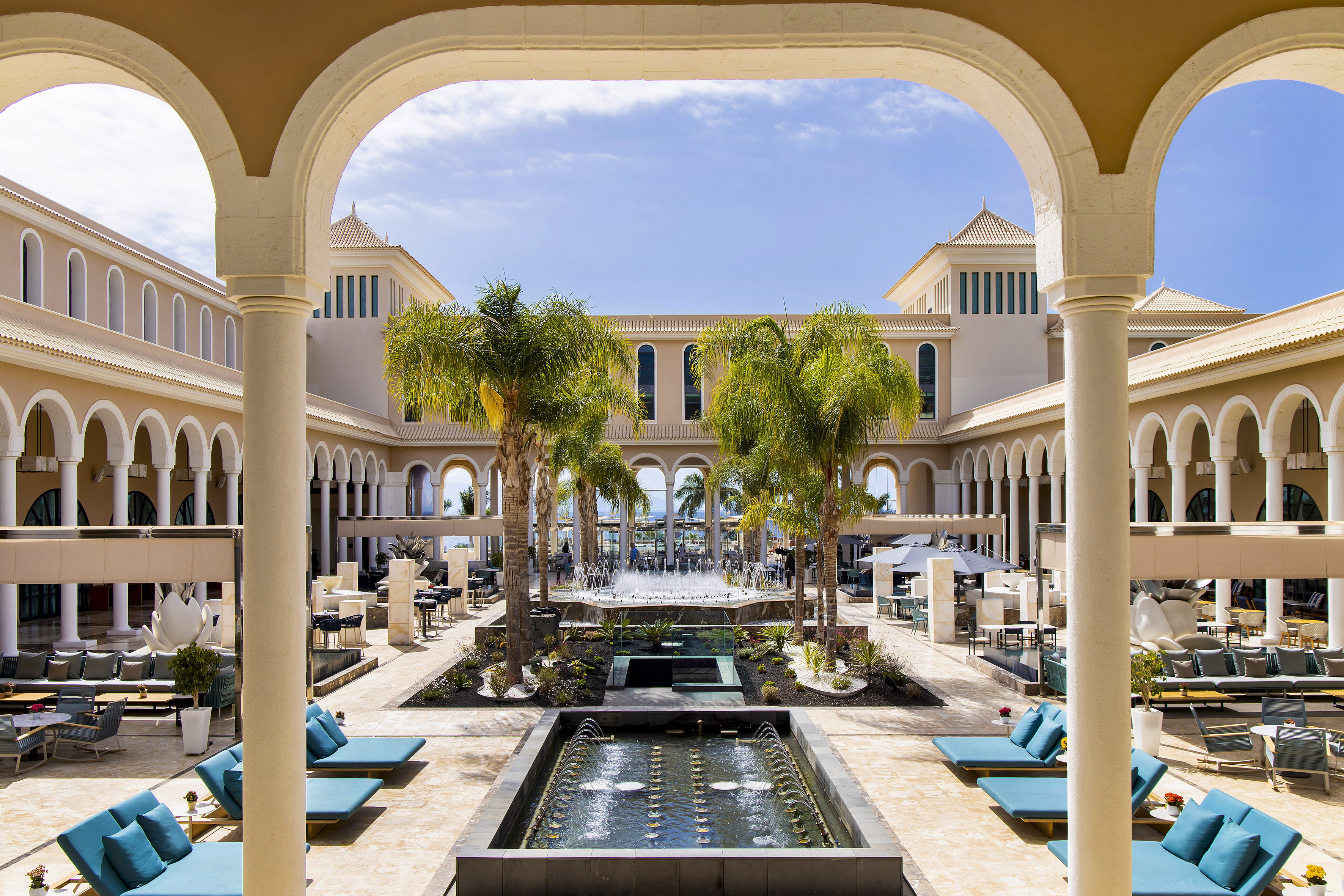 a pool with a fountain and chairs in front of a building
