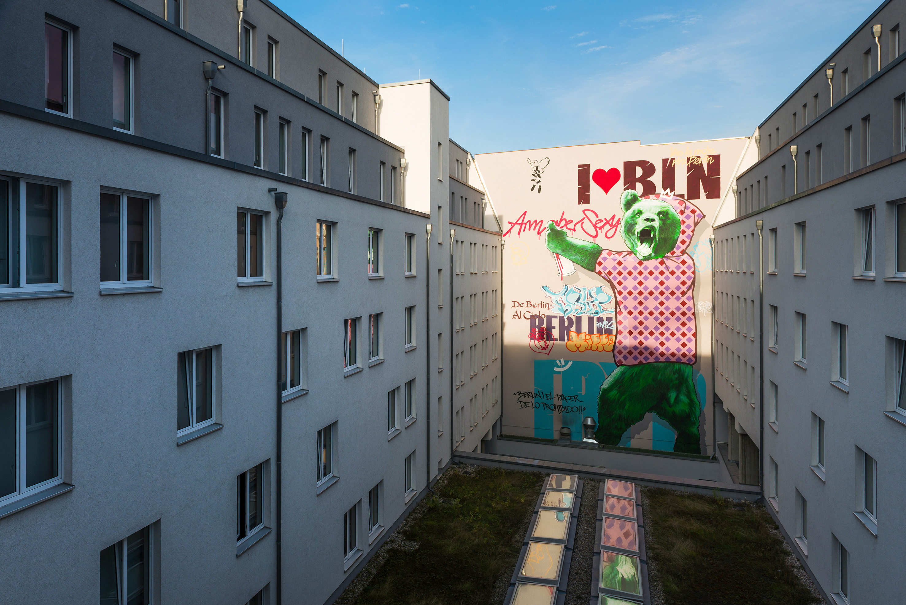Berlin courtyard with a large green bear graffiti mural, "I ❤️ BERLIN" text.